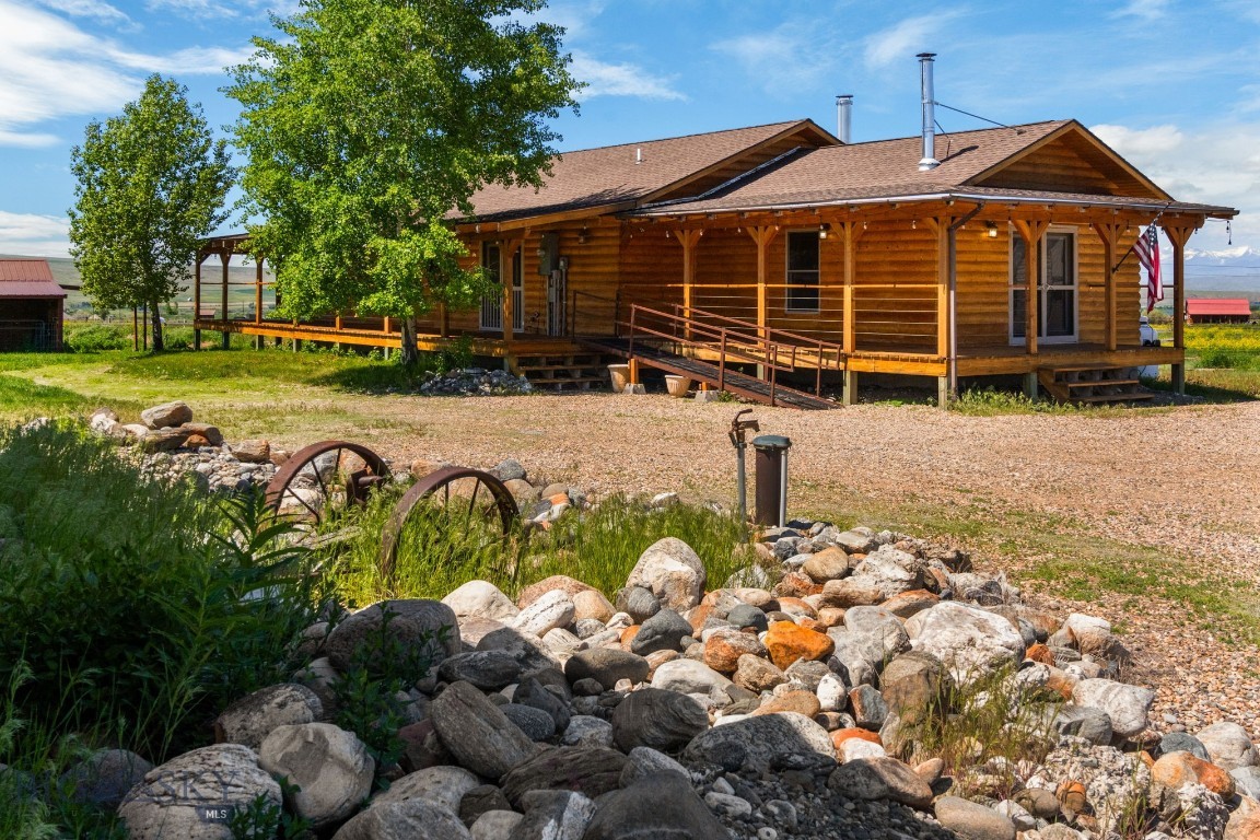 Enjoy the perfect balance of privacy, sustainability, and convenience with this beautifully designed 1704± SF home on 28.29± irrigated acres, just minutes from town. Surrounded by sweeping views of mountain ranges in every direction, this property offers an ideal setting for those seeking space, functionality, and natural beauty. The single-level home features a custom kitchen with unique Brazilian petrified river rock countertops, a cozy wood-burning fireplace with hand-selected stone from North Carolina, and a covered wraparound porch to take in the panoramic views. Heating is thoughtfully designed with an outdoor wood boiler, Rinnai propane heater, and supplemental wall units. One of the larger bedrooms includes a murphy bed, adding flexibility for guests or workspace. Outbuildings include a large shop, greenhouse, and chicken coop—perfect for gardening, small-scale farming, or hobby livestock. The land benefits from irrigation water rights and a solar power system to support sustainable living. A separate guest cabin offers one bedroom, one bathroom, a full kitchen, living area, and loft—ideal for visitors, extended living arrangements, or creative space. Whether you are looking to establish a homestead, enjoy quiet country living, or simply soak in the expansive Big Sky views, this property offers a rare opportunity with room to live, grow, and thrive.
