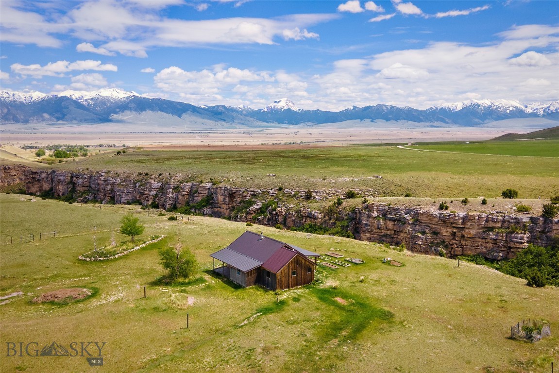 Tucked along the rim of WigWam Creek Canyon with forever views stretching across conserved ranchland and surrounding mountain ranges, this Montana property captures the kind of setting that’s becoming harder to find. Located on 5± acres in Shining Mountains II, the 1 bed, 1 bath log home with loft offers approximately 1,560± sq ft of rustic character and wide-open space just 15 minutes from Ennis.

Vaulted wood ceilings, large windows, and warm log accents bring the outdoors in, while the loft provides additional sleeping or flex space. The spacious bathroom features a large soaking tub perfectly positioned to take in the mountain views. Step outside to enjoy the dramatic canyon setting, abundant wildlife, and unobstructed southern views over the Bar 7 Ranch, protected by conservation easement.

Set up for enjoying the Montana lifestyle, the property includes horse corrals, loafing sheds, garden beds, and room to expand. HOA access includes trout-stocked Haypress Lakes, National Forest Service access, and miles of nearby trails ideal for horseback riding, hiking, ATVs, and exploring.

Conveniently located near the Varney access on the Madison River and less than an hour from Yellowstone National Park, this property offers privacy, recreation, views, and authentic Montana living.