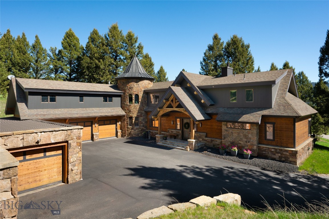 81 Steamboat Trail offers a thoughtful balance of architectural character, privacy, and open views across the Gallatin River basin toward the Gallatin Range and Porcupine Creek drainage. The home is distinguished by its craftsmanship, featuring historic structural beams salvaged from a Salt Lake City bridge and assembled using traditional dowel construction. These beams frame large-format windows that flood the living spaces with natural light and orient the home toward the landscape. A substantial stone fireplace anchors the main living area, complemented by hardwood floors and well-proportioned gathering spaces. A wide spiral staircase within the stone turret leads to a quiet reading landing and upper living areas, adding architectural depth and a sense of retreat. Each bedroom includes an ensuite bath and generous closet space. Multiple outdoor living spaces extend from the primary suite, main living areas, and upper entertainment level, positioned for privacy and views. The upper entertainment room features a full wet bar and direct access to an exterior terrace, creating a natural extension of the living space well suited for hosting. The layout balances openness with defined rooms, allowing the home to live comfortably at scale. A substantial, purpose-built workshop is a standout feature. Thoughtfully separated from the main residence, it offers exceptional flexibility for professional use, specialized projects, or storage, a rare find at any price point. Located within Porcupine Park, the property borders protected open space within a designated elk corridor that will remain undeveloped, preserving privacy and a lasting sense of openness. Lone Peak High School is within one mile, and Big Sky's world-class skiing and resort amenities are just 15 minutes away. Bozeman Yellowstone International Airport and Yellowstone National Park are each approximately one hour from the front doorstep, offering a rare combination of seclusion, access, and long-term livability.