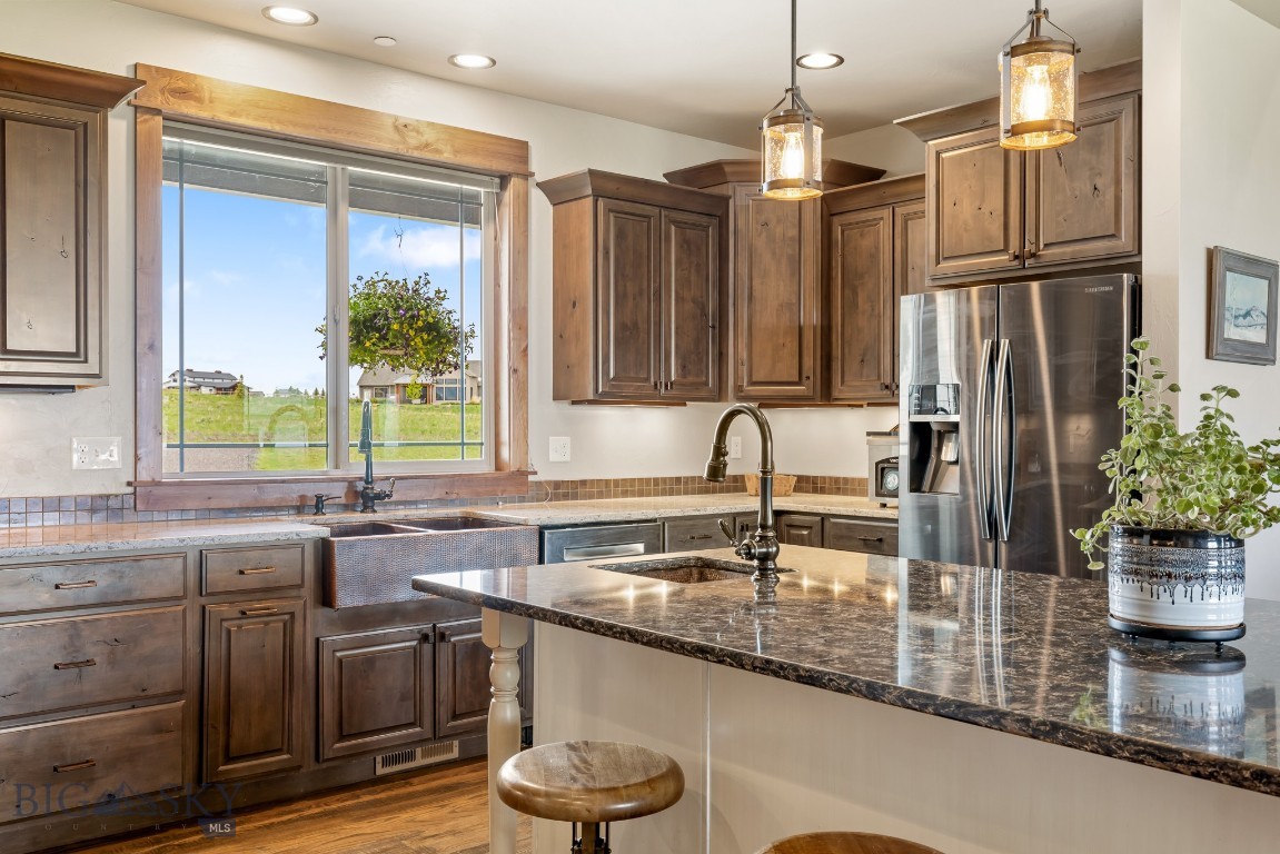 Discover the perfect blend of rustic charm and modern comfort in this spacious 3500+ finished home with breathtaking views of three mountain ranges just 30 minutes from Bozeman. The thoughtfully designed open floor plan invites comfortable living and effortless entertaining. All 4 bedrooms include a walk-in closet, and the home offers a dedicated office (with closet), a bonus room upstairs, and an oversized laundry room for ultimate functionality. The open kitchen features a extra-large island, copper farmhouse sink, a wet bar, walk-in pantry, and generous dining space—perfect for hosting gatherings. Rich Knotty Alder doors and cabinetry, along with rough-cut wood floors in the kitchen and dining areas, lend warmth and character throughout. Ceilings ranging from 9 to 11 feet enhance the home's expansive feel. Retreat to the primary suite, complete with a private sunroom, two walk-in closets, and large en-suite bath. Cozy up in the living area by the gas fireplace or step outside to relax under the large, covered patio—ideal for enjoying Montana’s summer evenings. An oversized three-car garage includes built-in shelving and a utility sink, and the property offers ample space to add a workshop or barn for horses. Designed with efficiency in mind, the home features multi-zone heating, a heat pump for increased air transfer of cool and warm airflow, two hot water tanks, a fire suppression system, and a lawn sprinkler system. Approx 2 acres with invisible fence of the almost 4 acre property. Of the approximately 5600 sq ft footprint, the unfinished 2,000+ sq ft basement is already framed, wired, and rough plumbed for two giant potential bedrooms/storage rooms, 2 main rooms and an additional bathroom—offering endless possibilities for customization.
