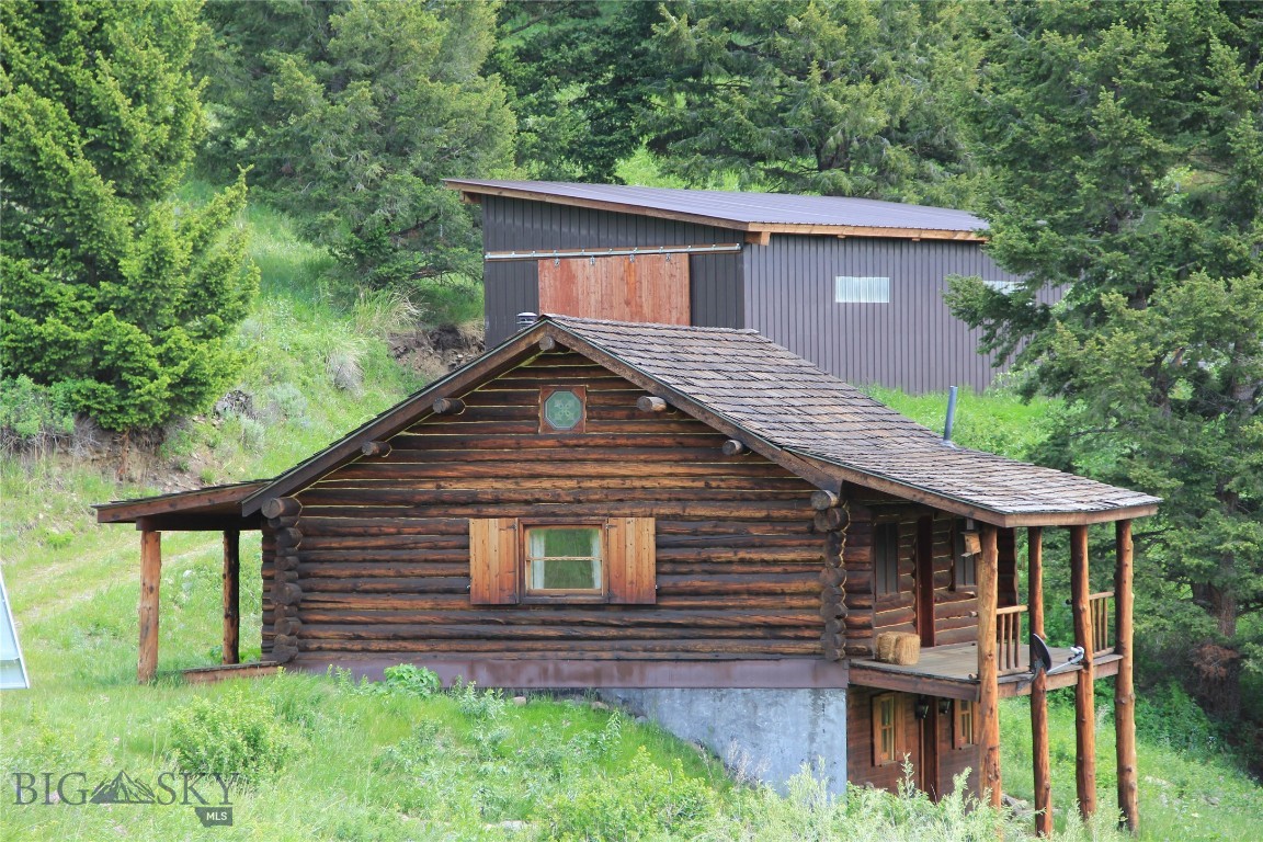 BORDERS FOREST SERVICE - Set above Ferrell Lake in the quiet Grizzly Meadows area, this log home offers the best of Montana self-sufficiency, and connection to nature. Built in 1999 and resting on 20+/- acres, the property offers unique value in self-sustainability as it is 100% powered by wind and solar energy. The 1,612-square-foot layout (not including loft) includes one bedroom and one full bathroom, with both front and back porches framing sweeping panoramic views of the Gallatin Mountains. A year-round creek meanders through the lower portion of the acreage, forming a natural wildlife corridor frequented by moose, bear, elk, deer and all other seasonal wildlife migrating from Yellowstone National Park whose grand entrance through the Roosevelt Arch is just 30 minutes away. With approximately 2,000 feet bordering Forest Service land, the property offers immediate access to public Forest Service, ideal for hiking, hunting, and opportunities to get in touch with nature. An 800-square-foot metal- sided pole barn, constructed in 2009, adds practical utility for vehicle storage or equipment needs. When you are in need of shopping or a night out, Emigrant lies just 40 minutes away where you will find Chico Hot Springs, fine dining at Sage Lodge, and lively summer concerts at the historic Old Saloon. Gardiner offers additional shopping, dining and opportunities for adventure at Yellowstone Raft Company, Montana Whitewater, and Flying Pig Adventures. Livingston with its cultural appeal is approximately an hour away while the trip to Bozeman will take 90 minutes. For those drawn to the quiet calm environment of solitude and self-sufficiency, this property offers rare opportunity for energy independence, unfiltered beauty, and proximity to one of the most iconic landscapes in the American West.
