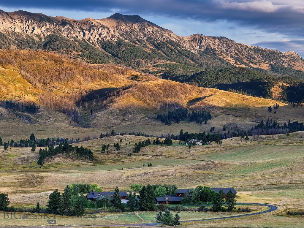 Set against the dramatic backdrop of the Bridger Mountains, Tepee Ridge Road is a rare legacy offering in the heart of coveted Bridger Canyon. Spanning approximately 97± deeded acres of rolling meadows, native grasses, and wildlife-rich landscape, this extraordinary property captures the essence of Montana living—where privacy, natural beauty, and convenience converge just minutes from both Downtown Bozeman and Bridger Bowl Ski Area. The estate is thoughtfully designed as a multi-generational retreat, anchored by a beautifully updated 5,386± square foot mountain modern main residence that blends timeless craftsmanship with warm modern elegance. Expansive windows frame sweeping views of the Bridger and Spanish Peak mountain ranges while filling the home with natural light. Reclaimed oak flooring, vaulted ceilings, stacked stone fireplaces, custom crafted Mahogany cabinetry, and refined designer finishes create an inviting atmosphere equally suited for intimate evenings or large-scale entertaining. Designed primarily for single-level living, the main residence offers multiple gathering spaces, a luxurious primary suite with a private covered deck, and seamless indoor-outdoor connectivity through expansive stone patios overlooking the surrounding meadows and mountain ranges. Complementing the main home is a charming 1,441± square foot guest residence featuring two bedrooms, two bathrooms, a heated garage, and warm interior finishes ideal for hosting family and guests in complete comfort. Additional improvements include a greenhouse, expansive shop, and large toy/RV barn, offering abundant space for recreation, equipment, horses, or outdoor pursuits. Wildlife thrives throughout the property, with elk, deer, sandhill cranes, and raptors frequently seen across the landscape, further enhancing the property’s remarkable sense of serenity and connection to nature. Tepee Ridge Road represents not only an exceptional lifestyle opportunity, but also a lasting investment in one of Montana’s most treasured landscapes.
