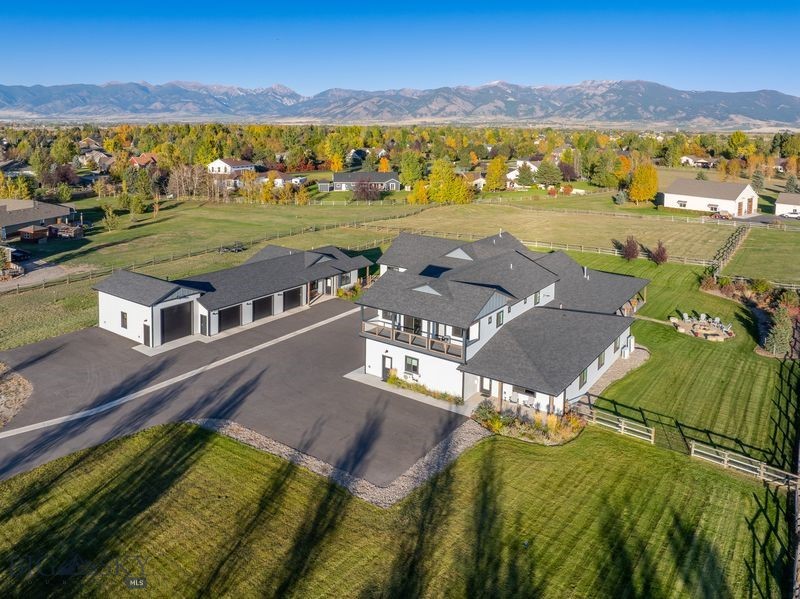 Looking for an modern, spacious property that has it all? This beautiful home could be it! It includes 6 luxurious bedrooms and 4 1/2 baths, an expansive open concept living space, huge family and recreation area, and a 4 car heated garage attached to the main house. In addition to mountain views and beautifully landscaped acreage with live water and room for horses, there is a guest house with a large heated 4 stall shop (including a space for a boat, RV, or camper) and a year-round creek in the front. Homes allowing horses yet still within the Bozeman school district are hard to find! Elegant space surrounds you as you walk into the vaulted living area, past the gigantic kitchen, and outside to an elaborate, fully covered wrap-around patio with Bridger Mountain views. Not only is the home conveniently located just outside of Bozeman city limits with easy access to essentially anywhere you need to be, it is filled with quality and attention to detail from floor to ceiling. Equipped with central vacuum, multiple heat and AC zones with humidification, Corbond insulation, multiple water heaters, Mezzo fireplaces, thermal protective windows, up/down cellular shades, security system, solid wood interior doors and trim, radiant heated floors in primary and junior suite, water treatment system with RO, and more! Entertaining large groups is a breeze with so much indoor and outdoor space, a rec room with wet bar, beverage fridge and dual tap kegerator, and a flagstone firepit to gather around! Both the main house and guest house yards are fenced with smooth wire to contain small dogs and the entire perimeter is fenced with post & rail. One of the garage stalls attached to the main house is equipped with a mini split for heat/AC and has finished walls and a vaulted ceiling, perfect for a golf simulator or a comfortable work area. The upstairs apartment in the main home can be utilized as a completely separate living space for relatives or guests, as it comes complete with kitchen, laundry, 2 spacious bedrooms, living area and bathroom. The 360 views and natural light are outstanding, and the covered balcony is great for enjoying the sunsets. The detached 2 bedroom 2 bath guest house could be utilized for a caretaker, nanny, or rental potential. It includes many of the same features as the main house including central AC, RO water, LVP flooring, up/down cellular shades, and its own fenced yard. 
See supplements for a list of amenities in this builder-owned home.
