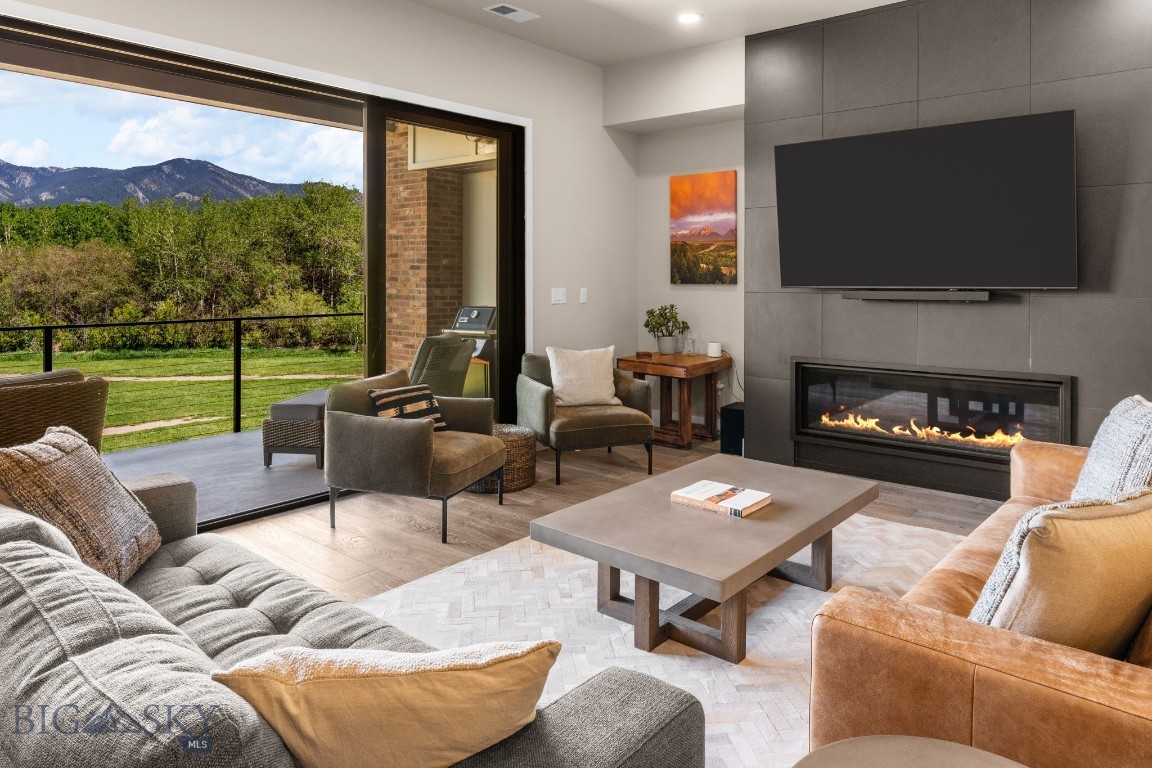 Experience the best of Bozeman living in this luxury modern townhome. This like-new single owner property features an open and inviting floor plan with beautiful finishes throughout - defined by its expansive windows that capture panoramic Bridger Mountain and Glen Lake views. The location is truly unmatched - just minutes from historic downtown Bozeman’s premier dining, shopping, with direct access to the city park and pond/beach and the Main Street to Mountains trail system that links to public lands and downtown Bozeman. Take the path to the neighborhood brewery or the local coffee shop  – or relax while admiring the huge mountain views from your deck. TFeaturing 4 bedrooms - each with its own bath - three elevated decks and plentiful living space, the floorplan is sure to please. The welcoming front entry features storage and access to main level ensuite bedroom or office/recreation room with a tiled ¾ bathroom. The open concept floorplan on 2nd is perfect for a variety of configurations – the chef’s kitchen features an oversized waterfall edge quartz island with counter seating, pendent lighting, GE Café appliances, 36” 6 burner range, wall ovens, tile backsplash and under cabinet lighting. The living room features a gas fireplace and huge windows that capture the protected mountain views across the city park. An additional bedroom on this level with upgraded carpet and private deck shares access to a hallway ¾ bath.
The top level features the primary suite and additional junior bedroom suite. The primary suite features vaulted ceilings, a wall of glass with additional upper-level windows facing the Bridger Mountains, an oversized walk-in closet with built-ins, solid surface flooring, a dual sided gas fireplace between the bedroom and luxurious bathroom. The primary bath features separate dual vanities, a vessel soaking tub, an oversized tile surround shower with bench and sequestered lavatory. The spacious junior bedroom suite just down the hall features an ensuite full bathroom and views towards the pond and park. Laundry washer/dryer convey. Extra deep 2-car garage with 2-car covered parking in the driveway. Property features central AC, on demand hot water and is prewired for a rooftop solar array. Landscaping and snow removal on sidewalks and driveway apron are responsibility of the HOA. Just 25 min to Bridger Bowl, 1 hour to Big Sky, minutes to blue ribbon fly fishing. Don’t miss the 360 VR Matterport Tour.