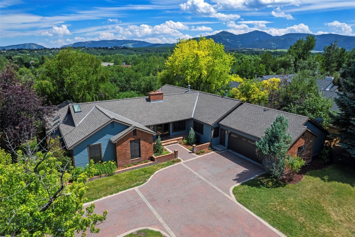A rare opportunity to own an exceptional legacy property in one of Bozeman's most established and sought-after neighborhoods. Originally designed and built by Hall of Fame homebuilder Clair W. Daines, with original building records identifying him as the owner-applicant, this distinguished residence reflects the craftsmanship, quality, and enduring design that made his work legendary throughout the Gallatin Valley.

Set on nearly an acre with Bird Spring Creek winding through the backyard, this remarkable 4-bedroom, 4-bathroom home with a dedicated office offers approximately 3,962 square feet of thoughtfully designed living space. Mature landscaping, expansive outdoor living areas, and the tranquil creek create a private Montana retreat, while city water and a private irrigation well make maintaining the lush grounds both practical and efficient.

Rich architectural details, warm hardwood floors, exposed beams, and generous living spaces create a timeless yet welcoming atmosphere. Designed for entertaining, the spacious kitchen features two dishwashers, a prep sink, abundant workspace, and seamless flow into the adjoining dining and living areas. A butler's pantry with a second oven and dedicated laundry area adds exceptional convenience, while a built-in surround sound system enhances everyday living and entertaining alike.

Comfort is ensured year-round with two air conditioning units and radiant heated floors. The vaulted primary suite offers a luxurious escape with exposed beams and a beautifully remodeled spa-inspired ensuite featuring dual vanities, an oversized tiled shower with dual shower heads, a freestanding soaking tub, and a private water closet.

The versatile floor plan includes spacious secondary bedrooms, multiple gathering spaces, and a finished lower level with a large family room, an additional bedroom, and a full bathroom—ideal for guests or multigenerational living.

Just minutes from downtown Bozeman, Montana State University, shopping, dining, and world-class recreation, this extraordinary property offers an unmatched combination of history, craftsmanship, privacy, and convenience. Legacy homes of this caliber rarely become available.