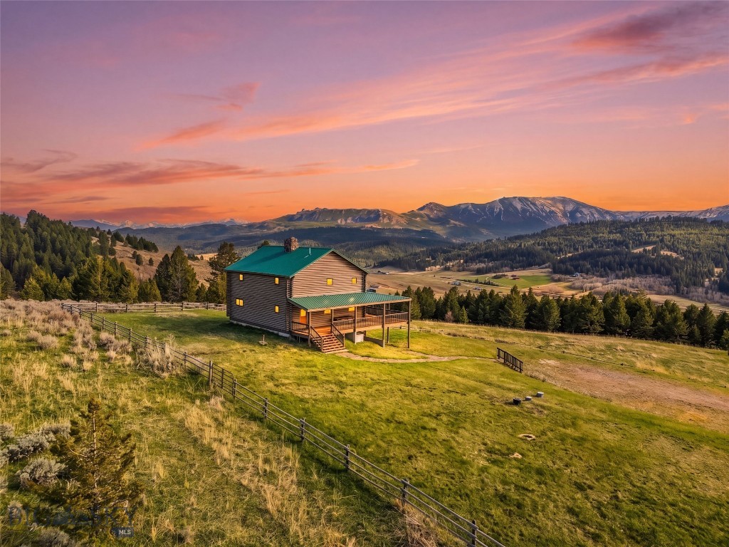 Positioned in the quiet hills of Trail Creek between Bozeman and Livingston, this beautifully renovated log home offers an exceptional opportunity to experience elevated Montana living across 27 private acres. Framed by sweeping mountain vistas, mature timber, and open meadows, the setting strikes a rare balance between tranquility, natural beauty, and year-round accessibility.
Blending authentic Montana craftsmanship with thoughtful modern updates, the residence has been extensively improved by the current owners with careful attention to both aesthetics and functionality. Custom windows by Montana Sash and Door invite abundant natural light into the home while perfectly capturing the surrounding landscape from nearly every room. The open-concept main living area was designed to gather and entertain, featuring smooth flow between the kitchen, dining, and living spaces, all centered around a dramatic stone fireplace accented by a handcrafted fireback from Montana Ironworks.
The upper-level primary suite provides a true retreat, complete with a private fireplace, en suite bath, and expansive views overlooking the valley and surrounding mountain ranges. Two additional guest bedrooms and a full bath offer comfortable accommodations with warmth and character throughout. On the lower level, the walkout basement expands the home’s livability with a family/game room, guest quarters, full bath, and a thoughtfully updated mudroom tailored for Montana’s outdoor lifestyle.
Recent seller improvements significantly enhance the property’s quality and long-term value, including a comprehensive exterior restoration with fresh stain and chinking, custom copper log end caps, refinished wraparound decking, and new exterior doors. Additional infrastructure upgrades—including a backup generator, secondary well with pump, and a 1,000-gallon in-ground propane tank—provide added comfort, efficiency, and peace of mind.
With room for light agricultural use, a detached two-car garage, and location within the LaMotte School District, this property presents a compelling blend of rustic elegance and modern convenience. Offering privacy, panoramic views, and timeless Montana appeal, this is a truly special mountain retreat equally suited for full-time living or a legacy recreational escape.