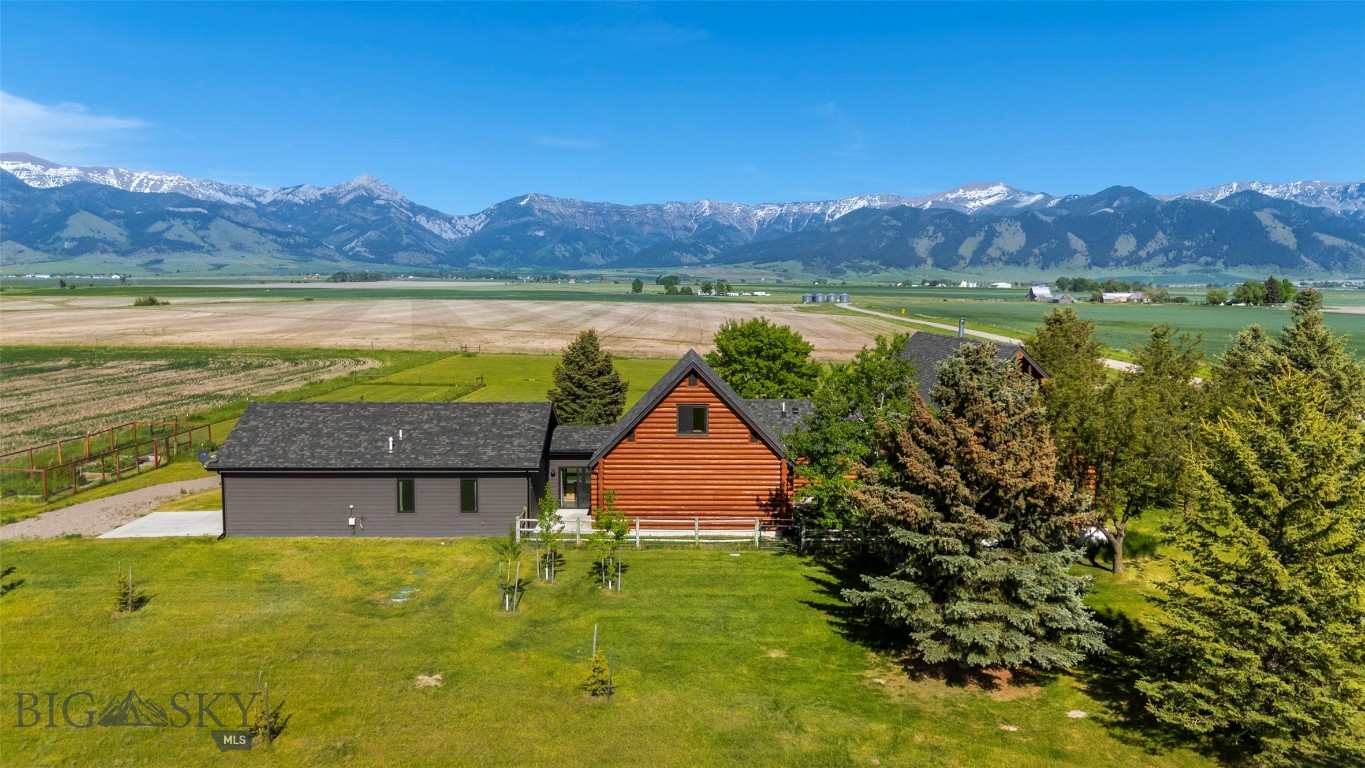 Experience refined mountain living in this extraordinary 8.6+/-acre estate, perched in Gallatin Valley's majestic Springhill area. Rustic elegance meets modern sophistication in this thoughtfully designed and recently remodeled custom log home. The main residence spans four bedrooms and three bathrooms, showcasing a main floor primary, soaring cathedral ceilings, and a stunning open-concept layout connecting the chef’s kitchen, dining, and living areas. Expansive windows frame panoramic views of the Bridger Mountains throughout the living spaces. Step out onto the expansive deck to enjoy unparalleled outdoor living—perfect for entertaining or savoring the stillness of the landscape. Upstairs, a large lofted family room with a private balcony offers an elevated retreat with commanding views. The basement provides two bedroom and versatility for remote work, library, or studio needs with two additional private rooms. Connected both from the outside or through an oversized 2-car garage, the meticulously built 1-bedroom, 1-bathroom guest residence (ADU), constructed in 2018 by ST Custom Homes, exudes modern charm and comfort. With its own full kitchen and living area, this residence is ideal for hosting guests, family or generating premium rental income. The entire guest suite and attached single car garage is heated by radiant in-floor heat. Additional updates and features: Remodeled bathrooms on main level (2), new kitchen, new windows throughout, whole-house generator system with dedicated propane tank, new boiler (2025), new basement carpeting (2025), updated lighting, and rebuilt new roof on main house (2024) and expanded front deck and balcony. The estate’s 8.6+/- acres come with valuable water rights and plenty of room for equestrian pursuits, boutique farming, or simply enjoying wide-open Montana skies. With a location that feels worlds away—yet is about 20 minutes from Bozeman, Yellowstone International Airport, and Belgrade - this rare property offers the best of Montana living. Space, beauty, and a sense of place that is truly unmatched.