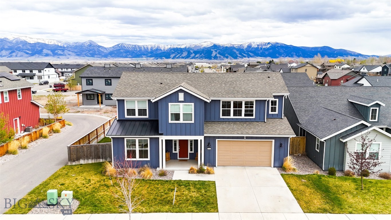 This one-of-a-kind 3322 soft, 4-bedroom, 3.5-bath home stands out with custom touches at every turn. From the moment you step inside, you’ll notice the thoughtful design, including a striking board-and-batten feature wall in the entry. The main level showcases a bright and spacious layout, with the living room, dining area, and primary suite all capturing breathtaking Bridger Mountain views—perfect for soaking in Montana sunrises. At the heart of the home, the custom kitchen shines with ceiling-height cabinets, sleek quartz countertops, and warm hardwood floors. Each bedroom features a walk-in closet, while the upper level offers a second primary suite. On your way up, a custom floor-to-ceiling bookshelf on the stair landing adds charm and character to the home. The laundry room, conveniently located just off the two-car garage, is complete with countertops and a full-size sink for added functionality. Step outside to enjoy the east-facing covered patio, ideal for entertaining, or let your four-legged friends play safely in their private fenced dog run.