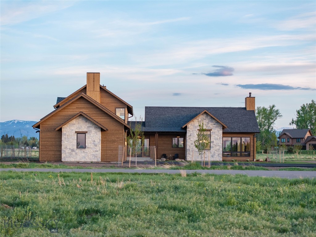 Set on a quiet cul-de-sac in the Coolwater neighborhood, this newly constructed home blends custom design with functional living, offering views of the Bridger and Hyalite Mountain ranges. Thoughtfully designed covered outdoor living spaces are positioned to enjoy balanced natural light throughout the day, while cedar siding and real stone accents complement the home’s warm mountain-modern aesthetic.
Designed for everyday living and entertaining, the layout creates a seamless connection between the kitchen, dining, and living spaces while still giving each area definition and purpose. The main living room is anchored by a custom stone fireplace and expansive windows framing the surrounding mountain views. Beam-accented vaulted ceilings and soft architectural arches add warmth, scale, and character throughout.
The kitchen features custom cabinetry, a panel-ready appliance package, under-cabinet and toe-kick lighting, and warm, refined finishes. A spacious walk-in pantry with an additional refrigerator provides exceptional storage and functionality. Integrated Sonos speaker system in the living room, primary bedroom, and primary bath.
Privately situated, the primary suite is designed as a true retreat with vaulted ceilings, wood beam accents, a statement wood accent wall, and direct access to a private covered patio. The home offers 4 bedrooms plus a dedicated office that can function as a fifth bedroom, along with 3 full bathrooms, a powder bath, and an upper-level bonus space for additional flexibility.
Situated on 2.4 acres, the property offers privacy, open meadow surroundings, and expansive mountain views while still being conveniently located near Bozeman and within the Monforton School District. The lot configuration also allows potential for an accessory dwelling unit (ADU).
Built by Triple Peak Construction
