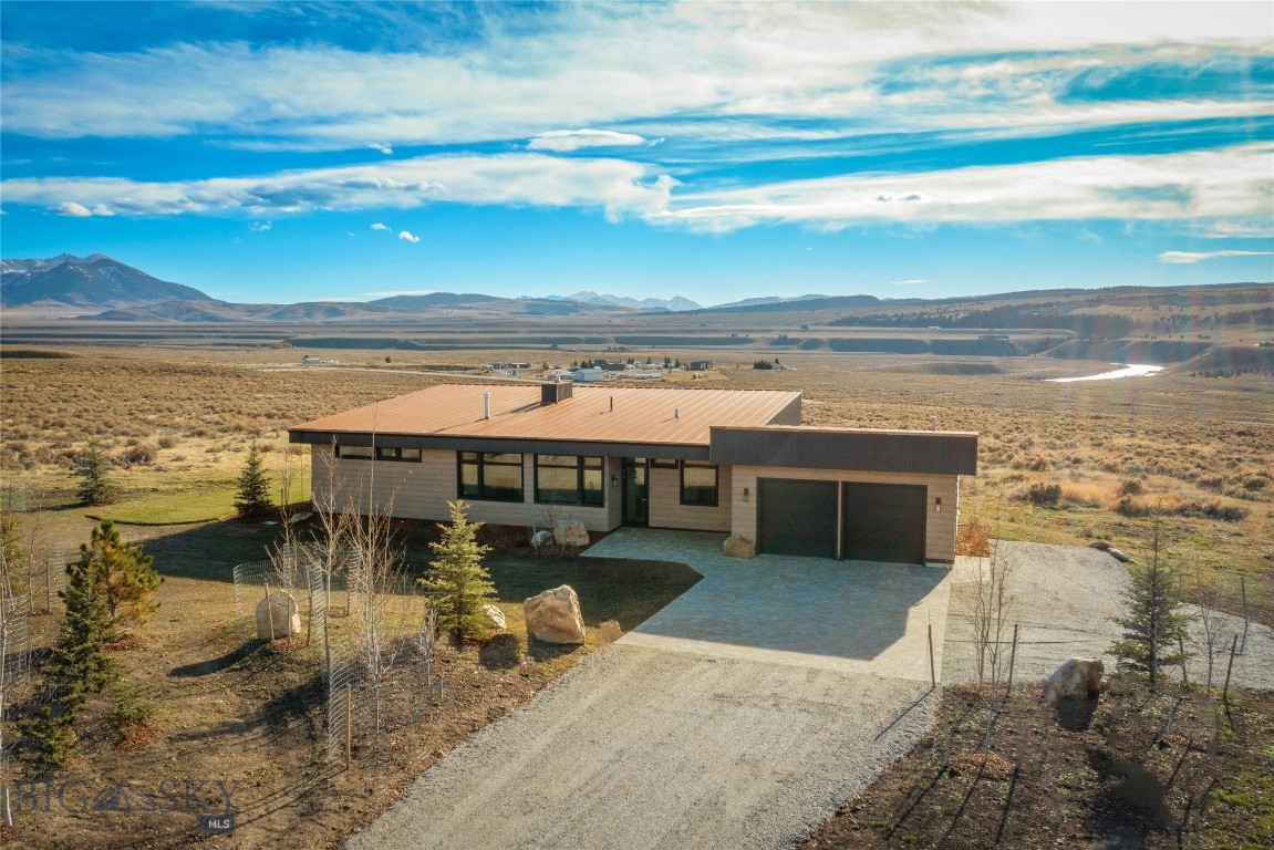 Tucked into over 23 pristine acres within the private Pine Butte Ranch, this luxury Scandinavian log retreat was built for those who understand that the best life is one lived close to wild places. The land rolls gently toward a conservation rich area, ensuring that the sweeping views of the Madison River, the Gravelly Range & the Centennials will never be interrupted — not by development, not by time. Native MT wildflowers drift through the yard, maturing trees hold their ground, and natural shrubs frame the property with an effortless, unhurried grace. The home itself was handcrafted in Finland from premium spruce logs, designed with passive solar efficiency & an architect's reverence for the landscape it inhabits. Expansive triple-pane windows pull the outside in, flooding every room with natural light & framing the mountains & river like paintings that change with the seasons. At the heart of it all, the great room centers on a striking limestone fireplace, flanked by floor-to-ceiling glass — a space that invites you to slow down & let the day settle around you after hours on the water or in the field. The gourmet kitchen was built for the kind of entertaining that happens naturally in a place like this. High-end appliances, custom maple cabinetry, and Calacatta quartz countertops set the stage, while a substantial honed Black Mist granite island anchors the room for effortless gatherings. The primary suite offers a private retreat within the retreat: a spa-inspired bath with a walk-in tiled shower, dual vanities & generous closet space. Two guest bedrooms share a thoughtfully designed Jack-and-Jill bath — ideal for family & friends that visit season after season. Outside, the wrap-around covered patio becomes its own room from spring through fall - a place to simply be present in a landscape that rewards attention. The oversized heated two-car garage with epoxy floors & a well-appointed utility space ensures the property functions beautifully in every season, from the deep cold of January to the long golden evenings of August. Location completes the picture. Minutes from the Three Dollar Bridge — one of the most storied fly-fishing stretches on the Madison River — and positioned conveniently near Yellowstone NP, Island Park & Henry's Lake, this property places you at the center of a true angler's & hunter's world. Blue-ribbon fishing - Backcountry hunting - Skiing within reach - and an expanse of wilderness adventure that never grows old.