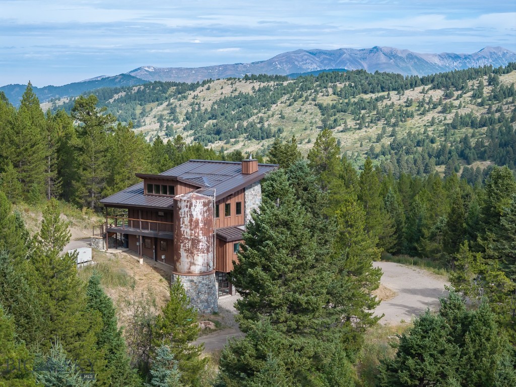 Discover your private sanctuary amid a majestic Montana landscape. This exquisite 2-bedroom, 2-bath mountain retreat sits on 20 wooded acres and offers the ultimate in tranquility and natural beauty. Immerse yourself with the comforting sounds of two year-round creeks that flow through the property. Take in the meditative peacefulness and spectacular views of the Bridger Mountain Range within the Great Room's wall of windows and with sliding glass doors that span 11' to step out to the wrap-around covered deck connecting indoor space with the natural world. You will love the quality workmanship and the meticulously designed stylish floor plan, from the absolutely breathtaking one-of-a-kind spiral staircase, with exciting custom lighting, to the elegant Southern pine hardwood floors and solid wood doors and cabinetry throughout. The kitchen has premium hi-end finishes with soft-close drawers, floating shelves, with theater-style lighting, plus quartz countertops, gas range and trash compactor. The living room includes a wood burning fireplace encased in gorgeous floor to ceiling stonework. The tiled main bathroom offers a private privy area and spacious tiled shower for two. An easy commute on I-90 that is only 18 miles from Bozeman's vibrant amenities and 25 miles from the Bozeman international airport. This mountain oasis provides a perfect balance of peaceful retreat with convenient access. Guests will enjoy, a separate detached studio style bedroom, 1-bath guest quarters with Montana views and a creek! Solar panels, two separate buried propane tanks, two wells, 2 state-of-the-art generators, and so much more! There is an additional private RV hook up area with power and water that ensures comfort for all. The possibilities are many, i.e., a year-round lifestyle, investment, corporate retreat or simply a wonderful Montana getaway! It could be yours!