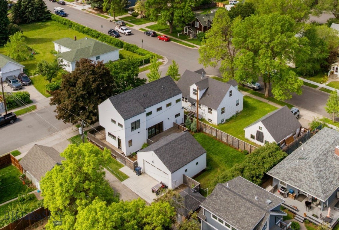 Tucked into one of Bozeman's most sought-after neighborhoods, just five blocks from vibrant Main Street and three blocks from Montana State University, this thoughtfully designed contemporary home offers the perfect blend of modern living, flexibility, and convenience. Built in 2018 and designed by Plum Architecture, the light-filled interior features soaring ceilings, expansive windows, and an open-concept main living space that feels both inviting and functional, with a powder bath conveniently located for guests. The main level flows seamlessly from the kitchen and dining area to an incredible wraparound deck spanning three sides of the home, creating effortless indoor-outdoor living and the perfect setting for entertaining or quiet evenings at home. Upstairs, two guest bedrooms, a shared full bath, a conveniently located laundry room, and a spacious primary suite with a walk-in closet and beautifully finished ensuite bath complete the second floor. The lower level ADU offers exceptional versatility with its own exterior entrance, kitchenette, living area, laundry, bedroom, and three-quarter bath, making it ideal for guests, multigenerational living, or additional income potential, while still connecting to the main home through an interior lock-off door. Outside, the oversized heated two-car garage is alley accessed, and the fully fenced backyard is framed by mature trees, established landscaping, and garden beds that create a peaceful retreat in the heart of town. The property was even recognized with the Neighborhood Revitalization Award from the Bozeman Beautification Advisory Board, a testament to the care and thoughtfulness that has gone into every detail. Adding even more character is the historic Bozeman trolley electrical building, a rare and unique storage space you simply won't find this close to downtown.