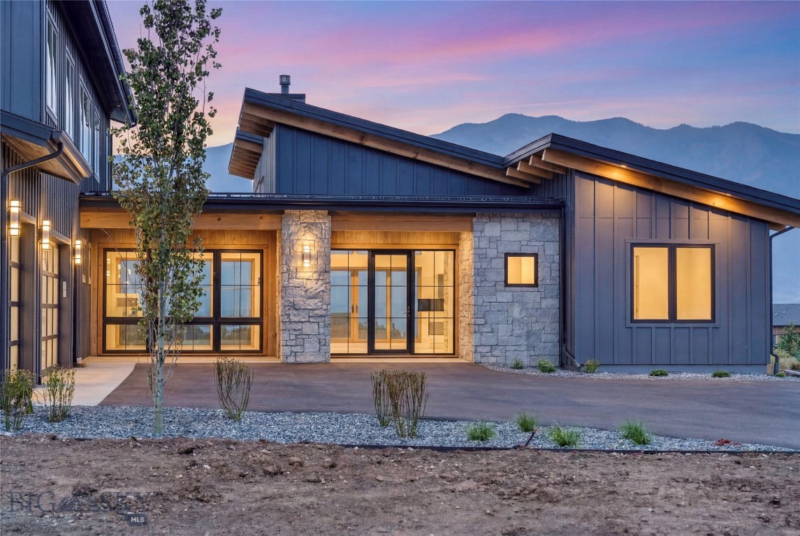 Set on 1.25 acres on the sought-after south side of Bozeman, this stunning new construction home in Home 40 blends elevated design, thoughtful functionality, and incredible views into one striking package. Backing to a peaceful pond with surrounding mountain views beyond, the setting feels both private and connected to everything that makes this community so special. Home 40 residents enjoy access to private ponds, miles of trails, a clubhouse, fitness center, and outdoor pool, all just minutes from Hyalite Canyon and downtown Bozeman. The home makes a strong first impression with beautiful stone accents, dramatic architecture, and a warm modern aesthetic. Inside, soaring ceilings and expansive windows flood the main living area with natural light, while a stunning fireplace with a stone hearth anchors the space. The kitchen was designed for both entertaining and everyday living, featuring Thermador appliances, quartz countertops, under-cabinet lighting, tile backsplash, a walk-in pantry, and seamless access to covered outdoor living spaces off both the dining area and kitchen. The main level offers a thoughtfully designed layout with a luxurious primary en-suite, spacious laundry room, powder bath, additional bedroom, and full bathroom and office. The office is entered through a custom glass wall, with floor-to-ceiling windows overlooking thoughtfully designed landscaping, creating a bright, architectural workspace with a calm, connected feel. The primary suite features dual walk-in closets, a freestanding soaking tub, dual-head walk-in shower, elevated finishes, and under-vanity ambient lighting. Just off the oversized three-car garage, the mudroom offers built-in storage, coat hooks, and space for organizing gear, while the heated garage offers ample storage. Upstairs, a generous flex space is surrounded by three additional bedrooms, all with walk-in closets. One bedroom includes an ensuite bath, while the other two share a Jack and Jill layout. Additional highlights include central air conditioning, seamless indoor-outdoor living, and a meticulously designed landscape plan featuring mature, statement trees that elevate the entire setting. Sophisticated yet inviting, bold yet timeless, this is the kind of home that turns heads while still feeling livable.