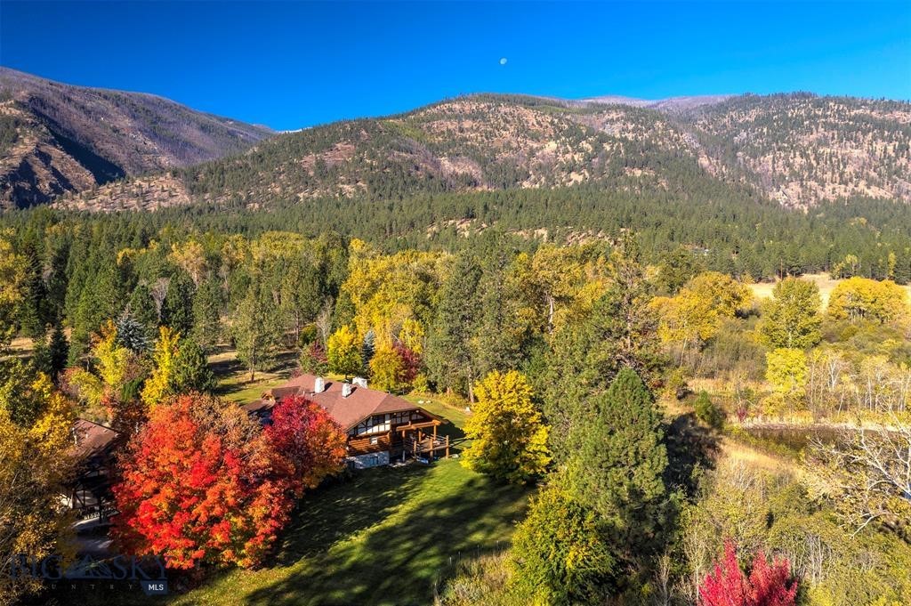 Welcome to Spring Mountain Sanctuary, ideally located in the northern reaches of Montana’s Bitterroot Valley. Minutes from the famed Bitterroot River and National Forest, this legacy property spans 84+ acres of classic pine trees, grassy forest meadows, a section of Tie Chute Creek, two spring fed ponds, and One Horse Creek cascading next to a custom-built 5 bed/3 bath Montana log home. Natural light fills the home, creating an inviting space for entertaining and family gatherings. Valuable flood irrigation water rights support a lush landscape and a private, serene environment where outdoor Montana living thrives.

Just 20 miles to Missoula and minutes from the Bitterroot River and National Forest, the property offers convenient access to recreation while maintaining exceptional privacy.

Water, Water. Tie Chute Creek runs for nearly half a mile across the property, which also features two spring-fed ponds, two irrigation ditches, grassy pastures for horses or cattle, and a diverse mix of pine and deciduous trees, including Maples and Oaks that offer brilliant fall color. One Horse Creek flows right near the home, enhancing the natural setting. The landscape blends mature timber and open lush meadows, creating both seclusion and expansive Bitterroot Mountain views. Large-acre neighboring parcels add to the peaceful rural setting.

At the heart of the property is a two-story, 6,800 sq ft custom-built, hand-peeled log home with 5 bedrooms and 3 bathrooms. Natural light flows throughout, creating a warm space for entertaining and gatherings. Also included are two offices, a craft room, living room stone fireplaces, cathedral ceilings, and multiple decks. Flood irrigation water rights support hay production and wildlife friendly sustainable land use.

The property includes several outbuildings: a 1,700 sq ft 3-car garage and woodworking shop with a two-bedroom, one-bath apartment above and a well house for lawn equipment. There is also a large tractor shed with shops that supported the cattle grazing, orchard and garden activities in the past. The land is perimeter and cross-fenced with jack-leg and barbed wire fencing, ideal for horses or a small cattle operation. County-maintained paved roads lead to the gravel driveway, ensuring reliable year-round access. The property spans four 20+ acre legal parcels.

Spring Mountain Sanctuary offers a rare combination of privacy, natural beauty, and usable infrastructure in a prime Bitterroot Valley location.
