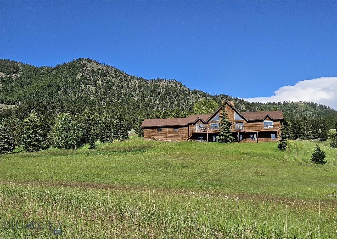 Perched on an elevated 10-acre homesite in the heart of Bridger Canyon, this exceptional property provides panoramic views of two mountain ranges – the nearby majestic Bridger Range and the dramatic Spanish Peaks stretching across the distant horizon. This setting embodies the very essence of “Big Sky” Country - expansive, peaceful, and unforgettable.

With room to roam in every direction, the property showcases a front-row seat to spectacular sunsets, snow-capped mountains, wildlife, and Montana’s ever-changing seasons.  The deck extends the living space outdoors, providing an inviting setting for dining and entertaining against a backdrop of wandering elk, deer, and soaring raptors. The hot tub offers the perfect place to relax and unwind beneath Montana's expansive skies after a day on the nearby trails or slopes.  

The interior is equally impressive.  A dramatic two-story stone fireplace anchors the great room, while a two-story wall of windows frames the breathtaking beauty of Bridger Canyon, filling the home with natural light and blurring the line between indoors and the surrounding landscape. Exposed timber beams, a vaulted ceiling, and custom wood flooring add warmth, character, and timeless mountain elegance.

Designed for both everyday living and entertaining, the home features four thoughtfully positioned bedrooms on two levels, a versatile loft ideal for a reading retreat, home office, or additional sleeping area, a walk-out lower level with a multipurpose room, additional utility room with abundant storage, and a separate bonus room for a private office, fitness room, hobby space, or studio.

Completing the property is a substantial 1,300+ square-foot outbuilding providing for vehicles, recreational equipment, horses, a workshop, or memorable gatherings. 

Every drive to and from the property is part of the experience, following the scenic beauty of Bridger Canyon through one of Gallatin Valley’s most sought-after landscapes. Downtown Bozeman is only 11 scenic miles away, with fine dining, shopping, cultural events, and everyday conveniences. Bridger Bowl's legendary "cold smoke" powder skiing is just 10 minutes from your door. 

Seldom does a property combine this level of privacy, acreage, views, and convenience in one of Bridger Canyon's most desirable locations. More than a home, this is a place to experience Montana in its truest form. 
Views – Privacy – Possibility. This is Bridger Canyon at its finest.