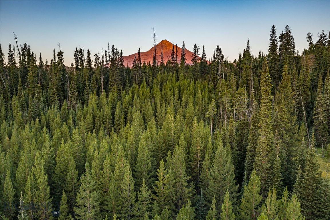 An extraordinary opportunity awaits in Big Sky, Montana: over 7 acres of pristine land showcasing sweeping mountain and valley views, a gently sloped terrain, and the rare privilege of bordering 360 acres of protected conservation land. This striking property offers unmatched privacy at the end of a quiet dead-end road, while still placing you within minutes of Big Sky’s world-class amenities. The neighboring conservation parcel provides unrivaled wildlife viewing and seamless access to low-impact recreation, including direct connections to Forest Service trails that lead deep into Montana’s backcountry.

Adding to its uniqueness, the northeast corner of the property touches a serene tributary commonly known as Beehive Creek, infusing the land with the calming presence of water. From here, you are also within walking distance of the coveted Beehive Basin Trail, one of Big Sky’s most celebrated hikes, offering dramatic alpine scenery and year-round adventure. The setting strikes an exceptional balance of untouched natural beauty and accessibility to Montana’s most sought-after experiences.

The location is simply extraordinary: just 10 minutes to the world-class skiing at Big Sky Resort, 15 minutes to luxury services and fine dining at the first stateside One&Only Resort, 15 minutes to Big Sky Town Center, and 30 minutes to the Montage Big Sky. Beyond Big Sky, you are a scenic hour’s drive to the wonders of Yellowstone National Park, the Yellowstone International Airport, and the historic charm of downtown Bozeman. Here, you’ll experience the rare combination of true mountain seclusion with effortless access to world-class amenities, dining, and cultural experiences.

The property’s flexible land-use opportunities further enhance its appeal. With over 7 acres, multiple structures can be built, allowing you to design an estate that fits your vision—whether that includes a guest house, barn, detached garage, or other spaces to complement your Montana lifestyle. Horses are permitted, opening the door to equestrian living against a backdrop of awe-inspiring mountain vistas.

This is more than a homesite—it is a sanctuary where conservation, privacy, and convenience converge. Whether you’re envisioning a family retreat, a legacy property, or an investment in one of Montana’s most coveted regions, this acreage captures the very essence of Big Sky living.