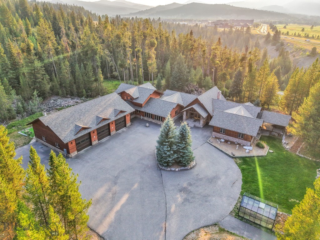 319 Skywood offers a rare combination of acreage, functional design, and proximity to Big Sky’s Town Center and Meadow Village. Set on over 5 beautifully landscaped acres with a total of 5 bedrooms plus an office/den/bunk room and 4 full & 2 half bathrooms, the home is designed for both everyday living and entertaining. Upon entry, you’re welcomed into an expansive Great Room with soaring ceilings and floor-to-ceiling windows framing views of Lone Peak. The space flows into a dining area and a large kitchen with double islands and high-end appliances. The main floor primary suite features a private covered porch with hot tub, offering a quiet retreat surrounded by mountain views and mature trees. Also on the main level are a second ensuite bedroom and a large bonus room, ideal for recreation or a cozy secondary living area. An attached 928± sq ft guest apartment connects to the main home yet has its own private entrance. Complete with a full kitchen, living area, bedroom, and bathroom, it provides flexibility for guests, multi-generational living, or rental use. The oversized three-car garage includes custom storage and connects directly to the home through a spacious mudroom with built-in boot dryers—perfect for Montana winters. The grounds are meticulously landscaped with a pond, waterfall, mature trees, and surrounding mountain views. Outdoor recreation is steps away with direct access to trail systems for hiking, biking, and Nordic skiing, plus the Southfork River sits just below the property, offering an incredible fishing spot just walking distance from home. Owners also have the option to build an additional 1,000± sq ft residence on the lot, offering room for future expansion or investment. 319 Skywood offers a truly unique balance of privacy, natural beauty, and access to everything Big Sky has to offer!