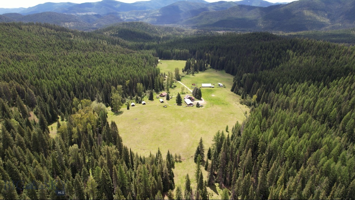 Broken Heart Ranch stands as a quintessential Montana legacy property. Homesteaded in the late 1800's, this secluded mountain ranch spans 80 acres, encircled entirely by U.S. Forest Service and State lands. The main residence, built in 1924, is a square-hewn log structure of 2400 sq ft, features an expansive open floor plan ideal for hosting. It has been modernized with updated plumbing and electrical systems while preserving its original stone fireplace. The covered porch offers panoramic views of the pasture and mountains, where a variety of wildlife including elk, moose, deer, and turkey, roam freely and call the ranch home. Accompanying the main house is a contemporary 1200 sq ft log guest house with two bedrooms, loft, and bathroom. "Cabin 6," a charming, vintage creek-front cabin, provides a serene wilderness retreat with complete amenities. Three additional rustic guest cabins are thoughtfully positioned across the grounds. The property also houses a historic log barn, echoing the charm of the old west, a modern four-car garage, and a quaint cottage-style greenhouse.  Broken Heart became a working dude ranch and hunting lodge in the 1950's. Back then the lodgers were offered horseback rides, campfire cookouts, hunting trips, and summer rodeos were held on the property.  Folklore suggests the ranch may have been a still site during prohibition. Today, thousands of acres of public lands border the ranch, offering extensive backcountry adventures on foot or horseback right from your doorstep. Recreational amenities include an 18-hole disc golf course, several campfire rings, and a small private pond, perfect for gatherings, exploring, and adventure. The recreational possibilities are boundless, with proximity to Clark Fork River for fishing and rafting, Silver Mountain skiing, hunting, hiking, snowmobiling, and various outdoor activities. Broken Heart Ranch promises ultimate seclusion with its end of the road privacy, nestled roughly an hour from both Missoula, MT, and Coeur d'Alene, ID, with convenient I-90 access. This distinctive estate is ideal for a family retreat, an Airbnb venture, or a personal sanctuary to relish the tranquility of western Montana.