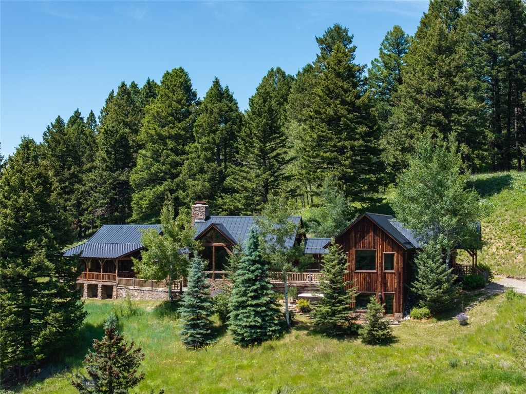 Set on 20 acres within the gated Cottonwood Creek Ranch, this exceptional mountain retreat is a collaboration between renowned architect Jonathan Foote and OSM Construction. Surrounded by towering pines, aspens, wildflower meadows, and views of Mount Blackmore, the 3,784± square-foot residence offers five bedrooms, four bathrooms, and a level of custom craftsmanship difficult to replicate.

Designed to feel inseparable from the landscape, the home blends naturally into the hillside beneath pitched rooflines, a dramatic stone chimney, and natural wood siding. Inside, the craftsmanship is evident from the moment you enter, where hand-hewn log walls, traditional wide chinking, peeled-log railings, reclaimed wood details, and wrought-iron accents establish the home’s distinctly hand-built character. Wide-plank hardwood floors, exposed timber framing, and substantial wood surrounds continue throughout the interior.

At the heart of the home, the vaulted great room features an expansive wall of glass that frames the views, while a monumental stone fireplace creates a dramatic focal point. The kitchen provides a refined contrast to the home’s more rustic materials, pairing alder cabinetry with honed soapstone countertops and stainless-steel appliances. Five bedrooms, including two primary suites, offer ample space for family and guests, while deep covered porches, stone terraces, and a private hot tub patio extend the living spaces into the landscape.

Current ownership has invested extensively in preserving the home’s character while thoughtfully enhancing the property. The handcrafted logs and exterior woodwork have been meticulously restored and maintained, and significant improvements include a new standing-seam steel roof, a detached two-car garage, recently updated kitchen, and numerous additional upgrades. A comprehensive list of improvements available upon request.

Although remarkably private, the property is 20± minutes from Bozeman’s restaurants, shops, galleries, and cultural amenities. The nearby South Cottonwood Trailhead provides access to thousands of acres of National Forest for hiking, horseback riding, mountain biking, and backcountry exploration, while Hyalite Canyon, blue-ribbon trout streams, Big Sky Resort, and Yellowstone National Park are all within easy reach.

More than a mountain home, this is a legacy property defined by enduring architecture, excellent craftsmanship, and a setting that feels entirely its own.