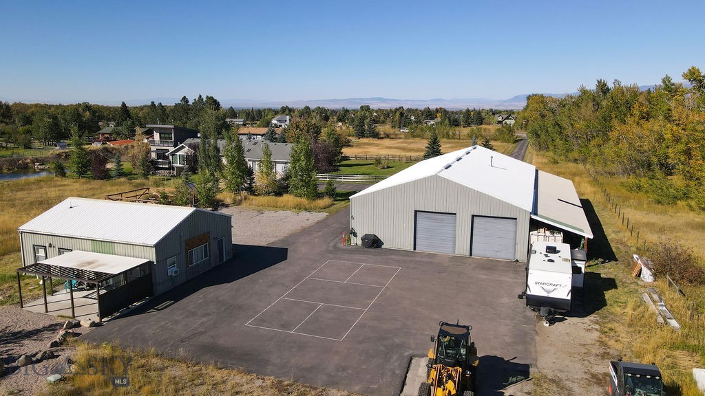 RARE FIND! NO COVENANTS, NO HOA AND NO ZONING! Set on 5 private acres at 9000 S 19th Ave, this remarkable 6380 sq ft estate offers a rare combination of natural serenity, expansive living, and exceptional versatility, all just 10 minutes from downtown Bozeman. Nestled near Hyalite Lake, the Gallatin National Forest, and miles of scenic trails, the property is surrounded by Montana’s most inspiring landscapes and outdoor recreation. The main residence features 3 spacious bedrooms and 3.5 baths, thoughtfully designed to embrace comfort, natural light, and breathtaking mountain views from nearly every vantage point. The home is perfectly positioned to overlook a beautifully landscaped, well-fed pond complete with a waterfall feature and sandy beach, creating a peaceful centerpiece that enhances the sense of tranquility throughout the property. Adding tremendous value and flexibility, the lower level includes a full two-bedroom apartment with a private entrance, ideal for extended family, guests, or long-term rental opportunities. A separate and stunning 1,200 sq ft ADU, currently operating as a successful Airbnb, further elevates the property’s strong passive income potential. For those seeking space to create, work, or play, the property boasts an impressive 5,000 sq ft heated shop with a 15’ x 100’ lean-to, featuring a pickleball court and countless additional amenities—perfect for recreation, storage, or business use. Centrally located between Big Sky Resort and Bridger Bowl, and within close proximity to world-class skiing, fishing, hiking, biking, and public lands, this estate offers unmatched access to everything Gallatin County has to offer—while maintaining a profound sense of privacy and calm. This is a true Montana sanctuary—a peaceful retreat, income-producing opportunity, and lifestyle property all in one. What about a corporate retreat? This property checks off all the boxes! You truly have to see it to fully understand the possibilities! Cross posted  as commercial MLS 408397. No Zoning per the county, however, County Sanitation may have additional requirements for commercial.