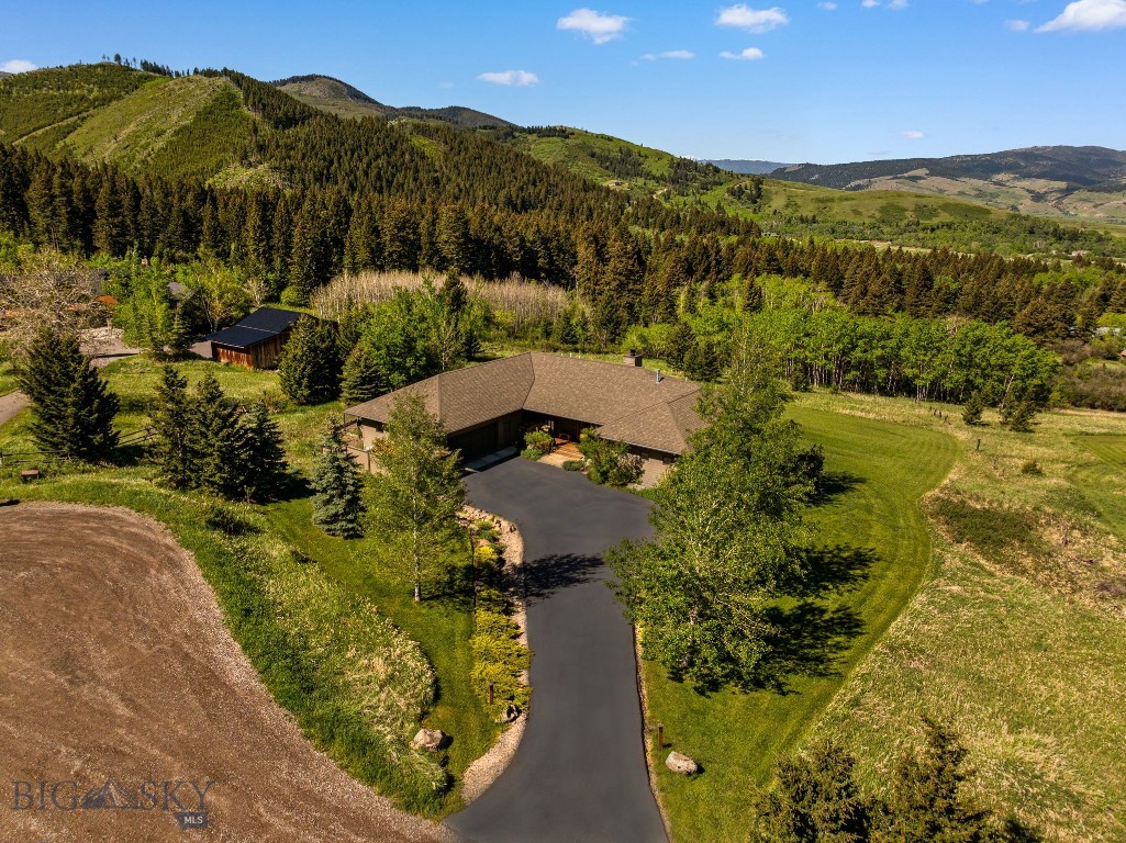 This custom 3 bedroom, 3.5 bathroom luxury mountain view home is located at 303 S. Big Elk Meadow Road in Gallatin Gateway, MT. Set at the end of a quiet cul-de-sac and perfectly positioned between Bozeman and Big Sky, the property offers sweeping views, exceptional privacy, and direct access to thousands of acres of public and state land for year-round recreation.

Expansive picture windows frame the dramatic mountain and valley views throughout the open-concept main living area, where rich hardwood floors, exposed beams, and a striking floor-to-ceiling stacked stone fireplace create a warm, elevated Montana ambiance. The gourmet kitchen features custom alder cabinetry, granite countertops, stainless steel appliances, generous storage, and a large walk-in pantry. An adjoining sitting and dining area is perfectly positioned to capture the views, while a separate flexible den offers ideal space for a home office, library, or media room.

The privately positioned main-level primary suite serves as a true retreat with direct outdoor access, dual walk-in closets, and two full bathrooms - one with a luxurious soaking tub and the other with a tiled walk-in shower. The bright, sun-filled walkout lower level includes two spacious guest bedrooms, a family room, a full bath, a powder room, and a large unfinished storage area with excellent potential for a future rec room or additional living space.

Outdoor living shines with generous upper decking and covered lower patios overlooking a broad mostly level lawn framed by beautiful mountain scenery, and an oversized 2.5-car garage with workspace and gated parking for vehicles, gear, campers, and toys.

With rare privacy, sweeping views, quality craftsmanship, and convenient access to Bozeman amenities and Big Sky skiing, this Gallatin Gateway home provides authentic Montana living in a truly special setting.