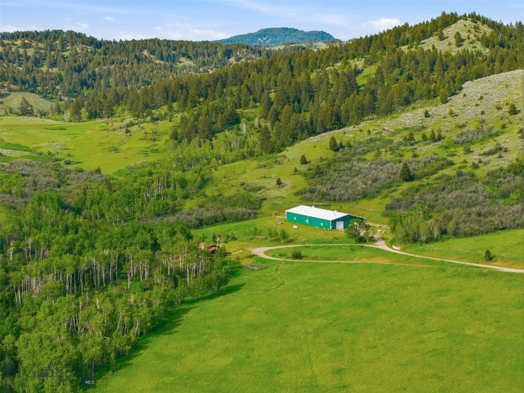 Experience the best of Montana living on over 65 pristine acres just 10 minutes from downtown Bozeman. Nestled among a grove of mature aspens and bordered by year-round Rocky Creek, this exceptional private and gated property offers remarkable privacy, breathtaking views, and a peaceful setting of rolling hills, open meadows, and abundant wildlife. The thoughtfully designed 2-bedroom, 1-bath home features an open-concept floor plan with quality finishes throughout. The inviting kitchen showcases granite countertops, a butcher block island, tiled floors, and ample space for gathering. Vaulted ceilings with exposed wood beams create a warm mountain-lodge feel, while the impressive floor-to-ceiling rock fireplace serves as the heart of the home. Large windows frame the surrounding landscape and bring the beauty of the outdoors inside. Step onto the covered porch and enjoy the soothing sounds of the nearby creek, spectacular sunsets, and endless opportunities for relaxation and entertaining. Equestrian enthusiasts will appreciate the impressive 8,100-square-foot barn complete with the possibility of an indoor arena and two horse stalls, making this an ideal horse property. Or perhaps, you have alot of toys or a car collection needing protection from the elements. Protected by a conservation easement that preserves the natural beauty of the land while still allowing for a second homesite, this property offers a rare combination of privacy, recreation, and long-term stewardship. Whether you're seeking a peaceful retreat, an equestrian property, or a place to build a lasting Montana legacy, this extraordinary acreage delivers the space, serenity, and convenience that are increasingly hard to find. And if you love to fish, 27inch Browns are a common occurrence.