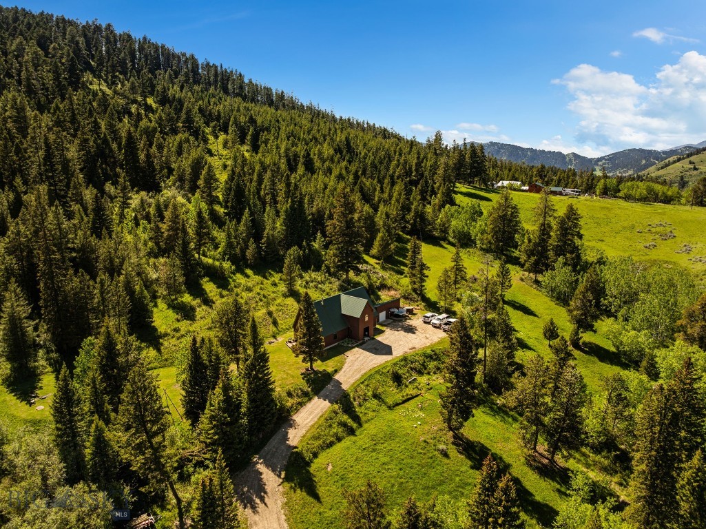 Remodeled home on 22 acres nestled privately up Trail Creek, just 20 minutes from downtown Bozeman! This property offers the ultimate mountain sanctuary—expansive, usable land surrounded by the quiet privacy of mature woods. Step inside the welcoming entryway to find a striking A-frame living space boasting vaulted tongue-and-groove ceilings. The open-concept kitchen, dining, and living areas flow seamlessly together, anchored by a cozy wood-burning stove perfect for chilly Montana evenings. You'll love the recently remodeled kitchen, which has been completely updated with brand-new cabinetry and appliances. The thoughtful layout features a main-floor office that leads into a bedroom, along with a one-and-a-half bath setup highlighting a relaxing, walk-up jacuzzi tub. Upstairs, you'll find two more generously sized bedrooms, a full bathroom, and a versatile loft space overlooking the living area below. Outside, a detached garage offers plenty of extra storage space for your gear and tools. The 22 private acres come alive with established trails ready for ATVs, horseback riding, snowshoeing, or hiking. Come springtime, the property transforms with an abundant, breathtaking array of seasonal wildflowers. Properties like this offer a truly rare lifestyle—true mountain privacy without sacrificing quick access to town. Take advantage of the best of both worlds at this Trail Creek sanctuary.