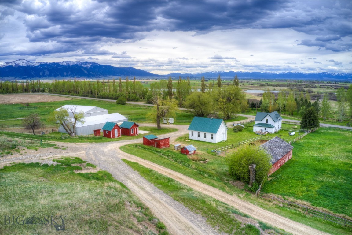 Rare opportunity to own a remarkable property offering open space, live water, two residences, and historic charm. The property features expansive mountain and valley views. Fully fenced, horse-ready pastures and two large metal barns make this an ideal setup for livestock or equestrian use. The extensively updated original farmhouse offers 2 bedrooms, 1 bathroom, and a large fenced yard. A 2003 manufactured home on a permanent foundation serves as the primary residence and was updated in 2017 with new siding and landscaping. The home features 3 bedrooms, an office, 2 full bathrooms, two living areas, a dining area, and a large kitchen. An oversized insulated metal garage provides ample space for vehicles, equipment, and storage. Both homes have underground sprinklers and are on separate wells and septic systems. Additional historic outbuildings include a bunkhouse, schoolhouse, and milkhouse, adding unique character and versatility. Conveniently located near Belgrade with easy access to Bozeman, this property offers a rare combination of privacy, functionality, and Montana heritage.
