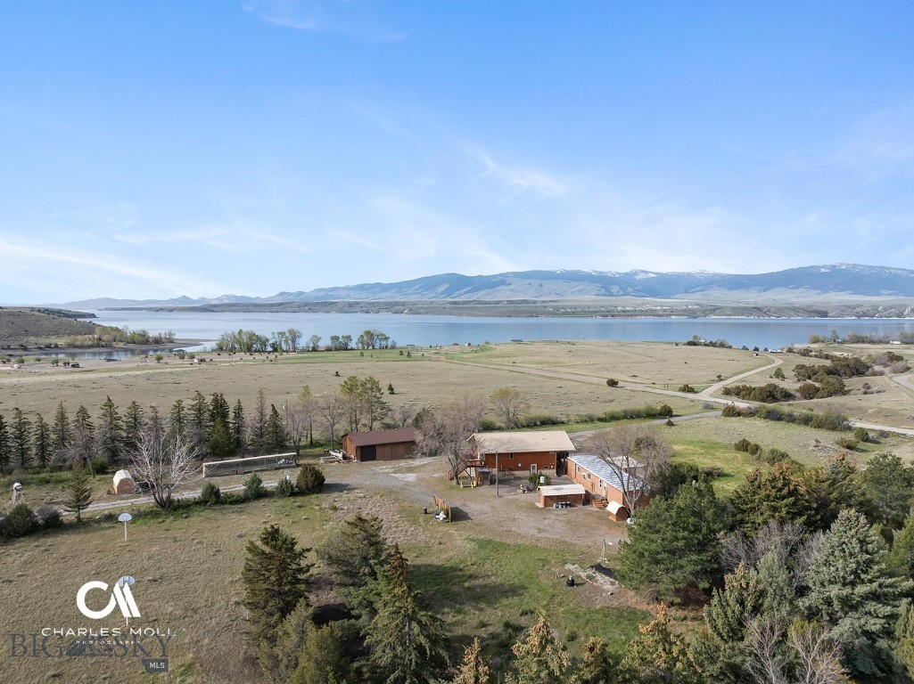 Overlooking Canyon Ferry Lake with sweeping views of the Big Belt Mountains, this 20-acre, fully fenced property gives you the space, privacy, and scenery that define Montana living. This is the place everyone wants to gather. Where fun is had and lifelong memories are made. You’re a stone’s throw from Goose Bay Marina and the boat launch, giving you easy access to boating, fishing, and year-round recreation. This legacy property features a log cabin, guest trailer, large 3-bay garage with shop, a huge steel boat/RV storage barn and two full hookup RV spots. The high-efficiency, two-story log home captures light and views through expansive upper-level windows that frame the lake and surrounding peaks. Aspen interiors bring a true lodge feel, while the open kitchen, dining, and living area create a natural gathering space. The upper-level bath includes a soaking tub with pristine lake views and walk-in shower. Front and rear decks extend your living space outdoors—ideal for morning coffee or evenings experiencing the gorgeous sunsets. The ground level offers 3 bedrooms (1 non conforming), a sitting area or office, a laundry/mechanical room area, and a second full bath, with storage integrated throughout. The guest trailer offers 3 additional bedrooms, 2 bathrooms, kitchen, dining, and living room. Separate heated three stall garage with shop, 40 x 60 storage barn for boats and RVs with extensive shelving, and fenced dog run round out the property. Mature, irrigated windbreaks of pine and deciduous trees provide privacy and protection, while deer and native birds regularly move through the property. Whether serving as a residence, vacation rental, seasonal getaway, multi-generational property, or recreational retreat, this rare 20-acre property provides privacy, versatility, and spectacular views in every direction.
