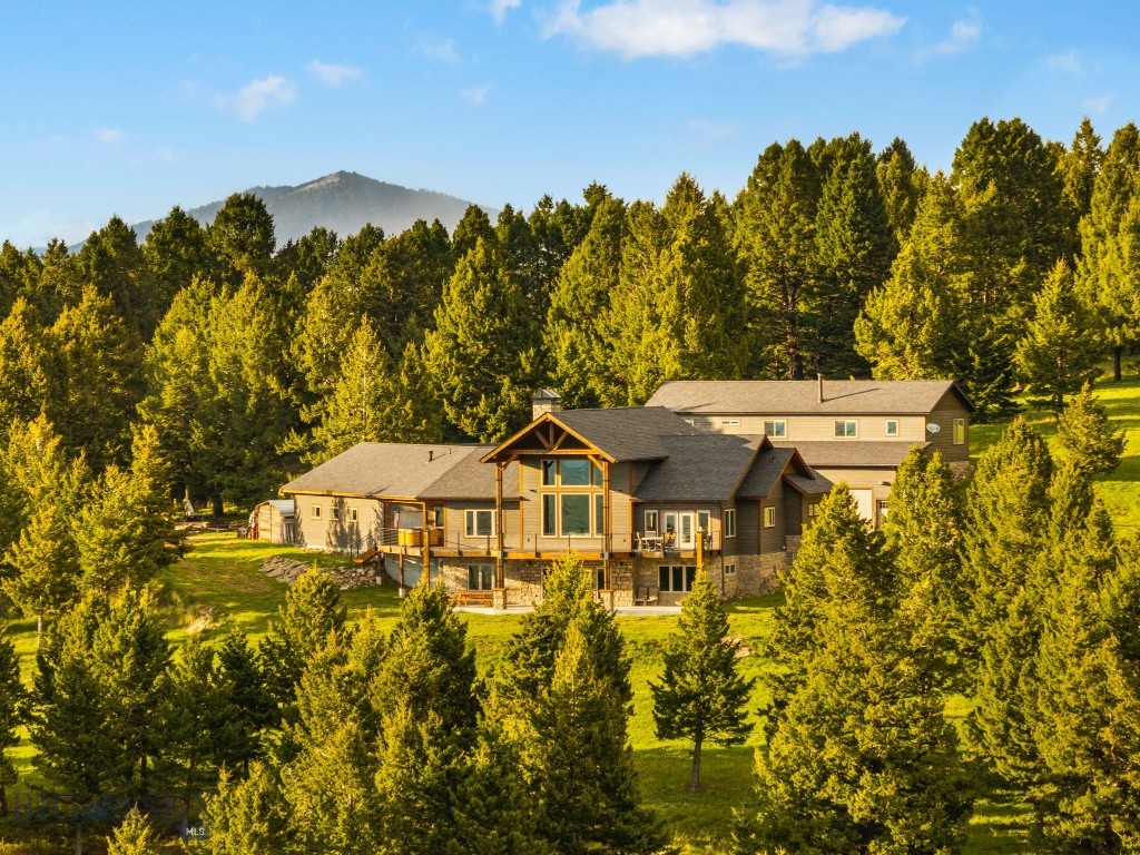 Tucked into the heart of Bridger Canyon, this extraordinary custom retreat is set across nearly 57 acres of breathtaking Montana landscape, where sweeping panoramic views stretch from the Gallatin Range and Hyalite Peak to the Spanish Peaks and all of Bozeman below. Equal parts private sanctuary and adventure basecamp, the property feels worlds away, yet sits just minutes from downtown Bozeman.

There is something undeniably magical about this land. Towering, lush forests, private trails, and endless places to explore create an experience that feels more like a mountain preserve than a residence. Wander through the trees and discover ridgelines and view corridors that reveal breathtaking vistas in every direction.

Thoughtfully crafted with Doug Fir timber sourced directly from the property, the home is a true expression of Montana living—natural, refined, and deeply connected to its surroundings. Inside, a massive stone fireplace anchors the main living space, complemented by rich wood flooring and expansive windows that frame the landscape like artwork and blur the lines between indoors and out.

The kitchen blends function and design with leathered granite countertops, premium appliances, and instant hot water, all flowing seamlessly into gathering spaces designed for entertaining. The main-level primary suite offers a private retreat with French doors opening directly to the hot tub, a spacious walk-in closet, and peaceful mountain views.

Radiant floor heating extends throughout the home. The walkout lower level was designed for both recreation and relaxation, featuring polished concrete floors, a theater area with projector, expansive wet bar, gym space, guest suites, and French doors opening to a covered patio overlooking the mountains beyond.

An oversized three-car garage with floor drains and a dog wash station adds everyday functionality, while an impressive 60x35 shop with additional living space above offers flexibility for guests, hobbies, or additional privacy.

A rare opportunity to own one of Bridger Canyon’s most captivating properties—where breathtaking land, unmatched views, and a lifestyle rooted in adventure and beauty come together in a setting that simply has to be experienced.