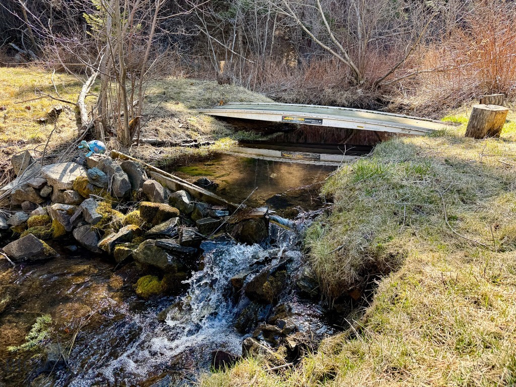 Located in the scenic Wolf Creek Canyon area of Lewis and Clark County, Montana, this 10.27-acre creekfront property offers a naturally beautiful private retreat and direct access to outdoor adventure. A quiet and secluded setting, this property is well-suited for buyers seeking a peaceful getaway or off-grid escape surrounded by wildlife and mountain terrain anytime of the year. The cabin is a solid structure designed for functional and comfortable use in a remote setting. The main level includes a kitchen, a 3/4 bathroom, a bedroom, and a utility room. Upstairs, the loft provides additional sleeping space with a unique layout that includes a bedroom at the top of the stairs and a second enclosed bedroom beyond it, allowing for guests or extended stays. A key feature of this property is its off-grid power system. The cabin is supported by mounted solar panels, battery bank, and inverter/charger system. The land itself is exceptional. A well-maintained trail leads from the cabin down to a year-round creek that runs through the property. Along the creek, you will find a beautifully cleared and park-like grassy area, complete with a walking bridge that enhances both access and usability. This space is ideal for relaxing, camping, or enjoying the natural surroundings. Wildlife is abundant and regular sightings include deer, elk, bear, wild turkey, moose, and a variety of bird species. The combination of water, cover, and nearby public land creates a strong habitat that supports year-round wildlife activity and excellent recreational opportunities in the area. Adding even more value, the property directly adjoins approximately 120± acres of state-owned public land, providing immediate access to additional ground for hiking, exploring, and recreation without the need to travel. Access to the property is convenient while still maintaining privacy. Little Wolf Creek Road, which leads to the property, is county-maintained and plowed, allowing for reliable access. The owner need only maintain approximately 600 feet from the county road to reach the property, offering a manageable balance of access and seclusion. This property offers a rare combination of off-grid capability, live water, wildlife presence, and public land access in a private Montana setting. It is well-suited for recreational use, year-round enjoyment, and those looking to invest in a secluded piece of land with strong natural features and outdoor potential.
