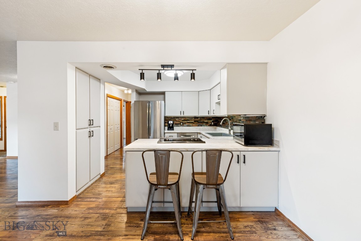 Tucked among mature trees in the desirable Southbrook community, this top-floor condominium offers rare privacy, tasteful updates, and easy access to everything Bozeman has to offer. This well-maintained 2-bedroom, 1-bath home features fresh interior paint, newer flooring, updated lighting, and an updated kitchen with modern countertops, newer appliances, and ample cabinetry.
The open living and dining area is anchored by a cozy corner fireplace and opens to a private deck surrounded by mature trees and landscaping—creating a peaceful outdoor retreat. Positioned on the upper level, the home is drenched in natural sunlight, adding warmth and brightness throughout the living spaces. The convenience of your own in-unit washer and dryer further enhances everyday living.
Additional highlights include gas forced-air heat, air conditioning, and a detached one-car garage complete with attic storage—ideal for extra gear or seasonal items. Located just minutes from Montana State University, trail systems, shopping, and dining, this home offers comfortable, low-maintenance living in one of Bozeman’s most convenient locations.