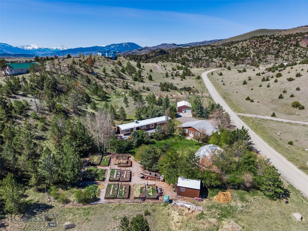 Live the life you've been dreaming about. Nestled on 4 sheltered acres on a quiet road, with breathtaking views of the Absaroka-Beartooth Range, this beautifully maintained 3-bedroom, 2-bath home offers the ultimate in country living — without sacrificing comfort or convenience.

The property's outbuildings and infrastructure set it apart: a large, fully insulated and heated light-filled 2-car garage with dedicated storage rooms; a separate shop with ample storage; and a solar dome greenhouse with an integrated fish pond -- together making this a true working homestead. A garden shed and raised beds, a large permaculture-fenced garden, and established fruit trees round out a property that has been lovingly stewarded for years — the results are visible everywhere, from the mature trees to the many perennial gardens.

Inside, the home has been thoughtfully updated with fresh paint, oversized windows to flood the space with natural light and frame those iconic mountain views, and a cozy wood stove to warm up by in the winter. Step outside onto the wraparound deck where a hot tub awaits — the perfect end to a day spent in the garden.

Perfectly positioned in the heart of Paradise Valley — an hour from Bozeman and 30 minutes south of Livingston. Besides the essentials, just a few minutes down the hill (groceries, gas & post office) the Emigrant area offers dining, live music, easy access to the Yellowstone river and legendary soaks at Chico Hot Springs. With the north entrance of Yellowstone National Park just 30 minutes down the road, the area offers so much: hiking, fishing, hunting, photography and fun on the river.  It's all right outside your door!

Easy access. Ultimate privacy. Stunning views. A gardener's dream and a self-sufficient sanctuary, all in one.