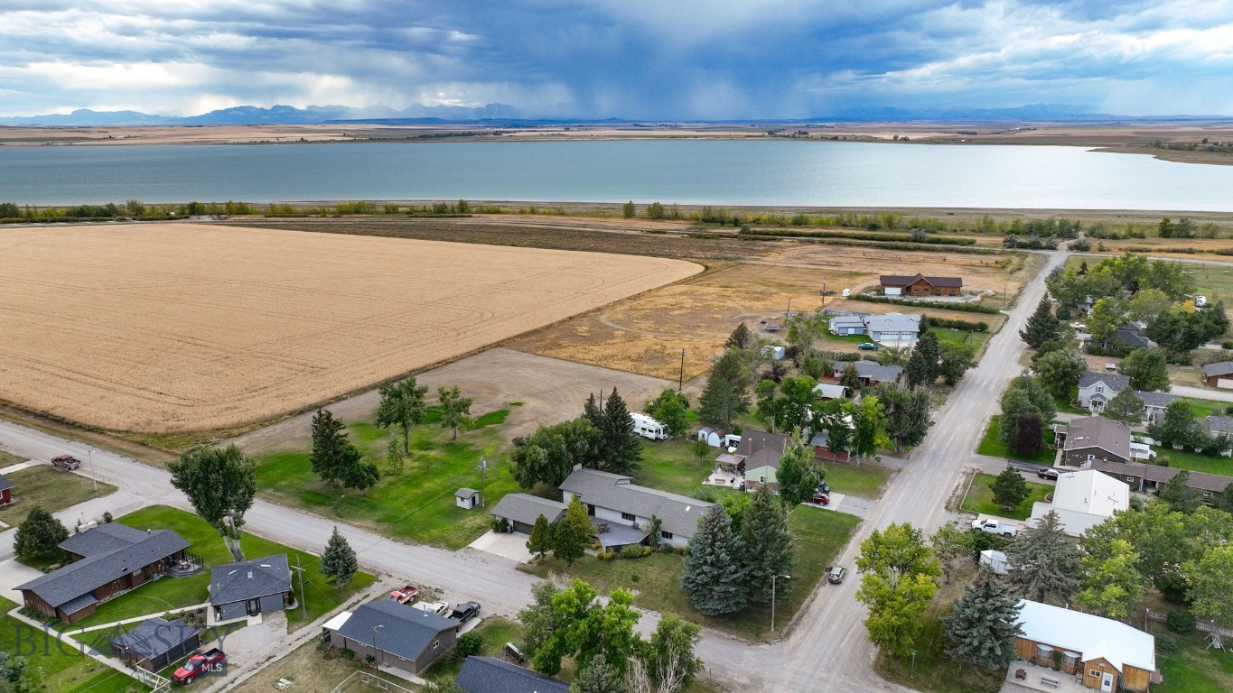 Come find one of Valier's most luxurious homes with high-end touches and an executive, rambler style. Enjoy unobstructed views of Lake Frances and a long expanse of the Rocky Mountain Front on a manicured corner lot with big shade trees. The garage is two-car, detached. The open floor plan, with an abundance of windows, invites entertaining with two living spaces, one with a handsome, modern fireplace and triple doors out to the huge patio. Dedicated dining room has built-in buffet with granite countertops. The kitchen has high-quality white cabinets, a dishwasher, built-in microwave, stainless refrigerator, stove/oven, black granite countertops and a center island. Ceilings are lined with real wood, designer lighting, some wainscoting and built-ins throughout. Bathrooms offer custom tile and vanities, plus enormous closets. The primary bedroom closet space is enormous and is a room in itself! The lower level has a non-conforming bedroom, 3/4 bathroom, a recreation room and abundant storage. Shed conveys. Valier is a quaint MT town surrounded by tons of recreation to include year-round fishing, hunting, and hiking. Glacier National Park is about a two hour drive.