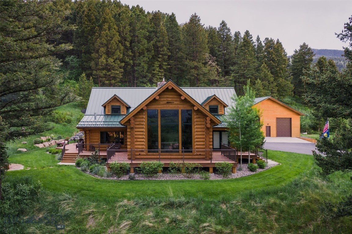 Cross a bridge over Bear Creek and follow the winding drive to discover an extraordinary 8.6± acre retreat bordering a vast expanse of State & Forest Service lands stretching toward Yellowstone National Park. With live water, evergreen forests, open meadows and majestic Bridger Mountain views, this rare property offers exceptional privacy and direct access to miles of hiking & horseback riding.
The main residence is a meticulously restored 4-bedroom, 3.5-bath log home that blends timeless Montana character with elevated modern finishes. Massive, beautifully maintained logs, circle-sawn wood floors, slate tile, and vaulted spaces create warmth and authenticity throughout. At the heart of the home, the expansive great room offers multiple gathering areas framed by picture windows and anchored by a dramatic two-story stone, wood-burning fireplace.
The remodeled kitchen pairs refined style with rustic charm, featuring sleek cabinetry, black granite countertops, premium stainless appliances, beverage cooler, wine storage and a butler's pantry. The main-level primary suite is a peaceful retreat with an ensuite bath and direct access to the outdoors, where mornings begin with birdsong and evenings end with the wind moving gently through the trees. An office, laundry area, and a newly rebuilt wraparound deck with wrought-iron railing complete the main level. Upstairs, three additional bedrooms—including one ensuite—feature vaulted ceilings, abundant natural light, and views of the surrounding landscape.
Thoughtfully positioned to capture panoramic mountain views and dramatic sunsets, the 2,850+ sf  Guest House constructed in 2019 is a 2 bed / 2.5 bath hideaway. Clean architectural lines, expansive windows, durable modern finishes, and a screened porch create effortless indoor-outdoor living. The upper level features a light-filled primary suite, kitchen, cozy living area with fireplace, and a laundry room complete with a dog wash station, while the lower level includes a guest suite, office, second living room w/ fireplace and plumbing for a future kitchenette/bar. A detached, heated two-car garage adds flexibility and convenience.
The detached 32x42 shop provides ample space for an RV, drift boat, Sprinter van, tractor, or other gear & equipment. Bring your horses and embrace a lifestyle defined by privacy, craftsmanship and endless recreation. This is a rare opportunity to own a true Montana legacy property.