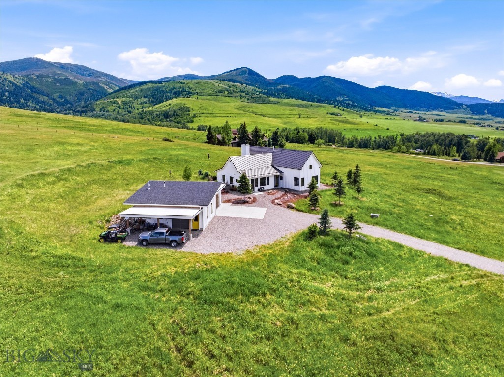 This architect-designed home is a statement of refined elegance set in an extraordinary mountain landscape. Thoughtfully crafted with exceptional-quality finishes throughout, the home features walnut doors and windows, dramatic Big Timberworks-framed trusses, and expansive walls of glass that blur the lines between indoors and out, creating a sense of being fully immersed in the surrounding landscape. A stunning travertine-tiled wood-burning fireplace, complemented by an additional gas stove, anchors the living spaces with warmth and character. Antique reclaimed wood, rich with history and timeless stories, adds depth and authenticity to this hidden treasure in Gallatin Gateway. Situated on 11± acres, the property includes three bedrooms, three bathrooms, and a detached garage with an expansive workshop offering endless possibilities for hobbies, storage, creative space, or additional functionality. Every detail reflects refined luxury and thoughtful design. The bathrooms provide spa-like spaces to unwind and recharge, whether beginning the day or relaxing at its end. Outdoor living is equally inviting, featuring beautifully landscaped gravel paths lined with natural boulders, a covered deck, a hot tub enclosure, and expansive spaces designed for entertaining or peaceful relaxation. A perfectly placed hammock invites quiet moments surrounded by nature and mountain air. Framed by breathtaking views of Gallatin Canyon and the surrounding mountains, this property captures the essence of luxury mountain living while remaining conveniently close to Bozeman. Elk, deer, and fox are frequent visitors, further enhancing the natural beauty and serenity of the property. The neighborhood also features a 16-acre park with Willson Creek flowing through it, trails throughout, a picnic area, and a fenced horse arena for owners to enjoy.
