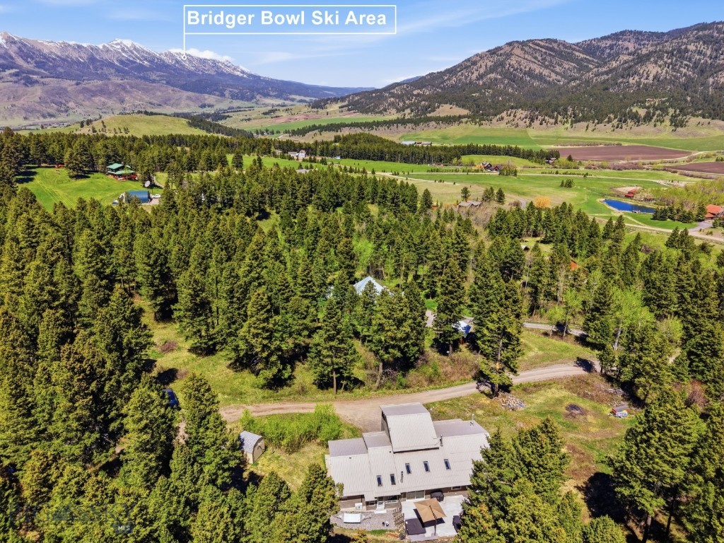 Looking for a home in the woods, close to world-class skiing and public land access? Look no further. Situated on 9.66 private wooded acres, this 4,097± sqft mountain retreat was originally built in 1982 and offers the perfect blend of comfort, space, and year-round recreation. Bridger Bowl Ski Area is located within an approximately 15-minute drive, while downtown Bozeman is about 25 minutes away and Bozeman Yellowstone International Airport is conveniently reached in approximately 30–35 minutes.

The main level features an open kitchen and dining area flowing into a spacious living room centered around a cozy stone gas fireplace. Right off the dining area, the large deck and hot tub create an excellent space for outdoor entertaining and relaxing among the trees. The primary suite is conveniently located on the main floor alongside two guest bedrooms, including one with an ensuite 3/4 bathroom, plus an office and a sun room filled with natural light. Upstairs, a large fourth bedroom or flexible bonus space opens to a covered balcony showcasing beautiful surrounding views. The basement level provides an additional large living area featuring a wood-burning stove, a 3/4 bathroom, ample storage space, and access to the attached one-car garage. The home is also equipped with a Generac propane-powered backup generator, providing added peace of mind and reliable backup power supply to the house.

Whether you are looking to move right in and enjoy the home as it is or bring your vision and creativity for a remodel, this property presents a rare opportunity to create your ideal Montana retreat. Peaceful wooded living combined with convenient access to skiing, recreation, and all the amenities of the Gallatin Valley makes this property truly special. Call your real estate professional today to schedule a private tour!