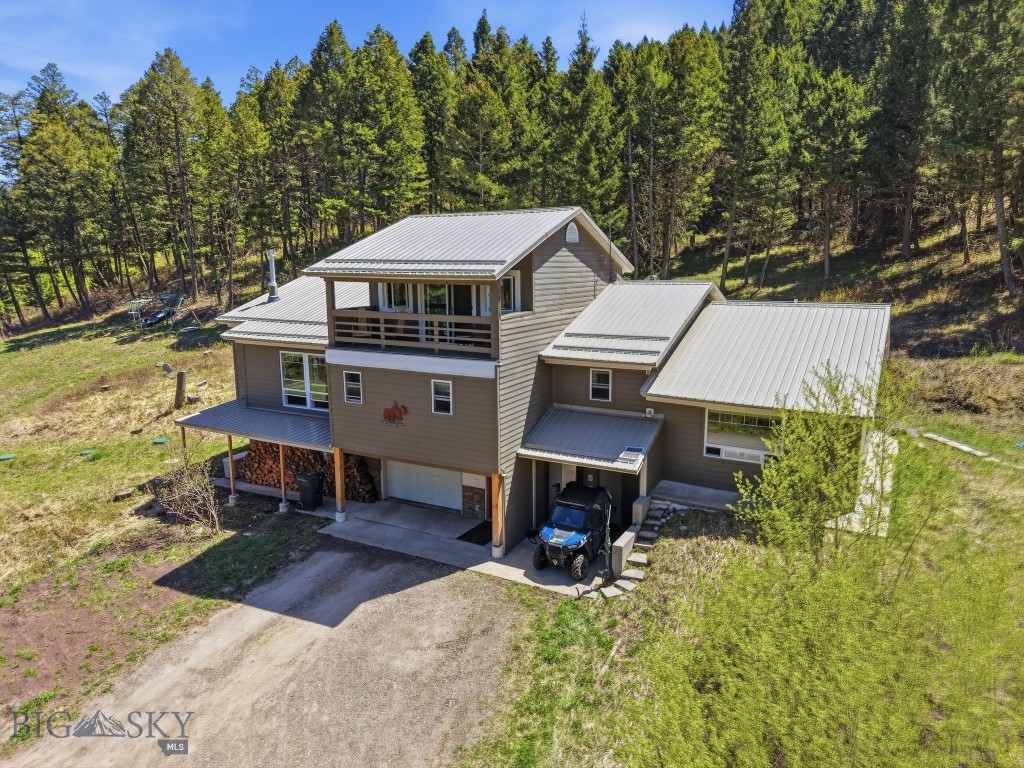 Looking for a home in the woods, close to world-class skiing and public land access? Look no further. Situated on 9.66 private wooded acres, this 4,097± sqft mountain retreat was originally built in 1982 and offers the perfect blend of comfort, space, and year-round recreation. Bridger Bowl Ski Area is located within an approximately 15-minute drive, while downtown Bozeman is about 25 minutes away and Bozeman Yellowstone International Airport is conveniently reached in approximately 30–35 minutes.

The main level features an open kitchen and dining area flowing into a spacious living room centered around a cozy stone gas fireplace. Right off the dining area, the large deck and hot tub create an excellent space for outdoor entertaining and relaxing among the trees. The primary suite is conveniently located on the main floor alongside two guest bedrooms, including one with an ensuite 3/4 bathroom, plus an office and a sun room filled with natural light. Upstairs, a large fourth bedroom or flexible bonus space opens to a covered balcony showcasing beautiful surrounding views. The basement level provides an additional large living area featuring a wood-burning stove, a 3/4 bathroom, ample storage space, and access to the attached one-car garage. The home is also equipped with a Generac propane-powered backup generator, providing added peace of mind and reliable backup power supply to the house.

Whether you are looking to move right in and enjoy the home as it is or bring your vision and creativity for a remodel, this property presents a rare opportunity to create your ideal Montana retreat. Peaceful wooded living combined with convenient access to skiing, recreation, and all the amenities of the Gallatin Valley makes this property truly special. Call your real estate professional today to schedule a private tour!