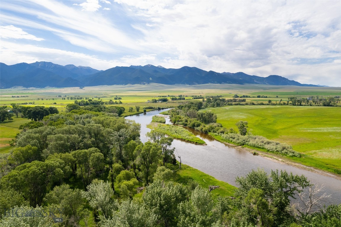Nestled in a pristine, private meadow along the banks of the Jefferson River, this exceptional 142-acre property offers the perfect blend of tranquility, recreation, and rustic elegance. The 2027 sq ft custom cedar home features 2 primary bedroom suites with full baths, highlighted by circular-sawn wood floors, a striking river rock fireplace, and an open-concept living and kitchen area designed for entertaining. Wraparound screened porches and a covered front deck provide the perfect setting to enjoy abundant wildlife and sweeping views, while air conditioning ensures comfort during the warmer months. An office area and cozy sleeping loft add flexible space for family and guests. Connected to the main home, the charming 896 sq ft log guest cabin is ideal for hosting, featuring a spacious primary bedroom with a full bath, along with an additional bedroom complete with six built-in bunks and a ¾ bath—perfect for gatherings with family or for friends that prefer an extended stay. Outdoors, the property truly shines with over half a mile of Jefferson River frontage, complemented by natural sloughs and spring- and river-fed ponds. This is a rare haven for bird hunters, anglers, and outdoor enthusiasts alike. Irrigated meadows, mature brush, and diverse habitat support abundant wildlife, including deer and moose. Additional improvements include a 30x50 shop/garage, offering ample space for equipment and storage. Whether you’re seeking a sportsman’s paradise, a private family retreat, or a classic Montana gentleman’s ranch, this remarkable property delivers it all. Conservation easement in place with Montana Land Reliance