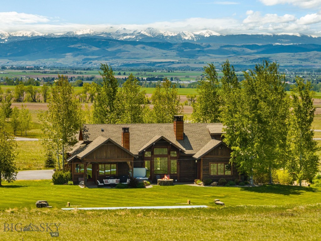 Positioned on 12 scenic acres and surrounded by neighborhood open space, this exceptional Montana property captures sweeping 360-degree views of the Bridger Mountains and surrounding ranges, farmland, and the wide-open landscape that truly defines the region. Designed by Brechbuhler Architects and masterfully built by Teton Heritage Builders, this custom home was thoughtfully crafted to embrace its remarkable setting, offering a seamless balance of refined comfort, exceptional craftsmanship, and connection to the outdoors. Inside, expansive windows frame the surrounding vistas while warm natural materials and vaulted ceilings create an inviting mountain-modern atmosphere. The main living spaces are designed for both quiet retreat and effortless gathering, anchored by a striking floor-to-ceiling stone fireplace and flowing naturally into the kitchen and dining areas, perfect for hosting family and friends after a day spent exploring the outdoors. The main-level primary suite offers a private sanctuary with its own fireplace and spa-inspired bathroom, while additional guest spaces and flexible living areas provide comfort and privacy for visitors, as well as multiple options for a work-from-home lifestyle. The lower level is designed with entertaining in mind, featuring a generous lounge space, a fireplace, a wet bar, and a temperature-controlled wine room—ideal for relaxed evenings and memorable gatherings. Outdoor living is equally inviting, with a spacious patio, built-in grilling area, hot tub, and wood-burning fire pit set against the backdrop of Montana’s expansive skies. The acreage offers room to roam and is well-suited for equestrian use, allowing for horses and future improvements such as a barn or guest house, ideal for those seeking a true Montana lifestyle. The property also includes a storage shed and ample space for continued customization. Surrounded by open space yet just a short drive to Downtown Bozeman, the Bozeman Yellowstone International Airport, and year-round recreation, this property offers a rare blend of privacy, views, and timeless Montana living.