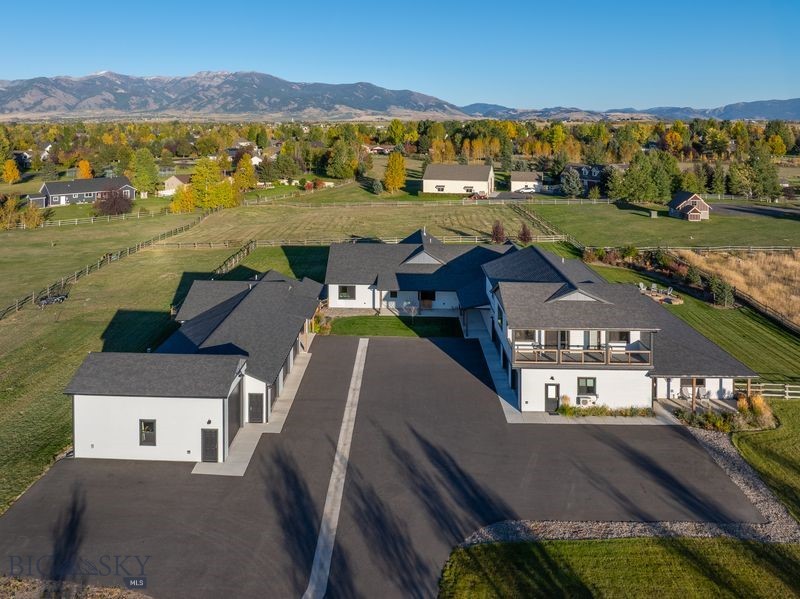 Looking for an modern, spacious property that has it all? This beautiful home could be it! It includes 6 luxurious bedrooms and 4 1/2 baths, an expansive open concept living space, huge family and recreation area, and a 4 car heated garage attached to the main house. In addition to mountain views and beautifully landscaped acreage with live water and room for horses, there is a guest house with a large heated 4 stall shop (including a space for a boat, RV, or camper) and a year-round creek in the front. Homes allowing horses yet still within the Bozeman school district are hard to find! Elegant space surrounds you as you walk into the vaulted living area, past the gigantic kitchen, and outside to an elaborate, fully covered wrap-around patio with Bridger Mountain views. Not only is the home conveniently located just outside of Bozeman city limits with easy access to essentially anywhere you need to be, it is filled with quality and attention to detail from floor to ceiling. Equipped with central vacuum, multiple heat and AC zones with humidification, Corbond insulation, multiple water heaters, Mezzo fireplaces, thermal protective windows, up/down cellular shades, security system, solid wood interior doors and trim, radiant heated floors in primary and junior suite, water treatment system with RO, and more! Entertaining large groups is a breeze with so much indoor and outdoor space, a rec room with wet bar, beverage fridge and dual tap kegerator, and a flagstone firepit to gather around! Both the main house and guest house yards are fenced with smooth wire to contain small dogs and the entire perimeter is fenced with post & rail. One of the garage stalls attached to the main house is equipped with a mini split for heat/AC and has finished walls and a vaulted ceiling, perfect for a golf simulator or a comfortable work area. The upstairs apartment in the main home can be utilized as a completely separate living space for relatives or guests, as it comes complete with kitchen, laundry, 2 spacious bedrooms, living area and bathroom. The 360 views and natural light are outstanding, and the covered balcony is great for enjoying the sunsets. The detached 2 bedroom 2 bath guest house could be utilized for a caretaker, nanny, or rental potential. It includes many of the same features as the main house including central AC, RO water, LVP flooring, up/down cellular shades, and its own fenced yard. 
See supplements for a list of amenities in this builder-owned home.
