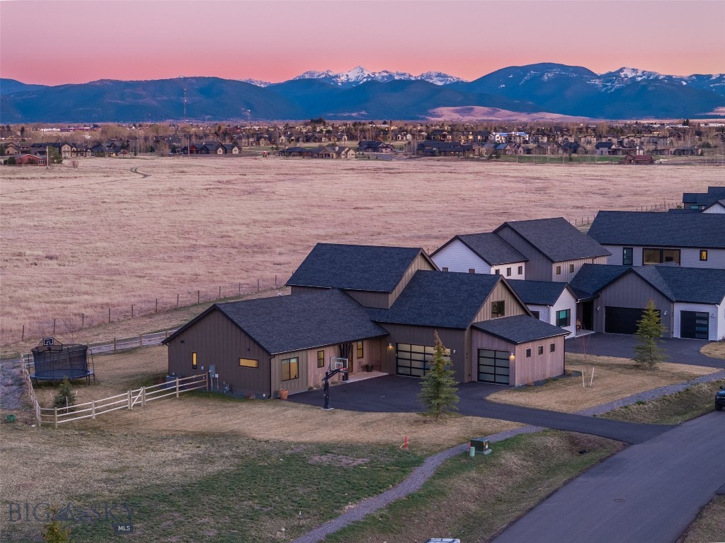 Big Sky views meet modern Montana living. Set on nearly half an acre (.419± ac) in one of Bozeman’s most sought-after areas, this thoughtfully designed 3,035± sq ft, 4 bed, 3 bath home delivers clean architecture, a functional layout, and sweeping Gallatin Valley views that evolve with every sunset. Inside, a light-filled open-concept living space features vaulted ceilings, exposed beams, and expansive windows that frame the mountains. The kitchen blends style and function with a large quartz island, high-end appliances, and seamless flow into the dining and living areas—ideal for entertaining or everyday living. The main-level primary suite offers a private retreat with a spa-like bath and direct outdoor access, while a second main-level bedroom provides flexibility for guests or a home office. Upstairs, two additional bedrooms and a full bath create separation and space. Positioned on one of the largest lots in Creekside Meadows, with open space to the north and east, the property offers rare privacy and unobstructed Bridger Mountain views. The fully fenced and landscaped backyard is designed for both relaxation and play. Enjoy Montana living year-round from the covered front and back porches or unwind on the back patio as the sun sets over the valley. Built in 2023, this home also features a three-car garage and a spacious paved driveway. Modern design. Expansive views. Montana lifestyle—dialed in.