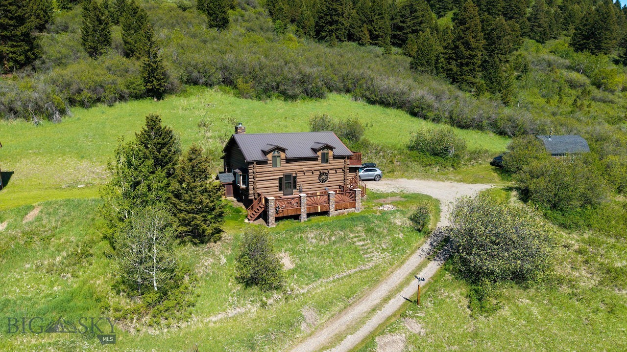 As seen on HGTV's Bath Crashers, this unique log cabin has driveway access to paved Trail Creek Road and is located about 20 minutes to Bozeman or 45 minutes the back way to concerts at the Old Saloon in Emigrant. Perfect getaway cabin to relax and watch deer and elk graze on the surrounding mountain hillsides or the occasional moose in Meadow Creek below and enjoy the sun-drenched side of the valley from the several outdoor spaces. 
Efficient use of space in the custom kitchen with electric cooktop, dual wall ovens, built in microwave and accented with rustic, circle sawn wood cabinets, creative tiles and stacked cultured stone walls.
The living area features a mix of log and rustic timbers with a large, north-facing bay window, wood floors, high, vaulted ceiling and a Vermont Castings, wood-burning stove in the corner with travertine tiled hearth and wall surround.
The main-level primary bedroom is modest, but an incredible surprise awaits you with bathroom that was designed and built by HGTV's Bath Crashers (featured on Season 12 Episode 12). Their design team created a luxurious bath accented with rock, tile, glass, wood and metal. Two person, walk-in shower, complete with a picture window to the great outdoors, wall and ceiling shower heads and custom tile throughout. Large soaking tub facing custom wood shelving with a built-in, electric fireplace.
Upstairs there are two, small bedrooms with non-traditional closets, loft office area, an eclectic and artistic tiled bathroom with walk-in shower and a perfect place to soak in the rays on the large, south-facing wood deck.
Outbuildings and extras - 13' x 19.5' storage barn with a gambrel roof, 15' x 24' detached small garage and multi-level playhouse house with storage and attached henhouse. Back up generator with it's own 500 gallon propane tank.
NOTE: Wood Post Foundation that may limit financing options. There is a partial foundation on the primary bathroom. Water is a spring fed well.