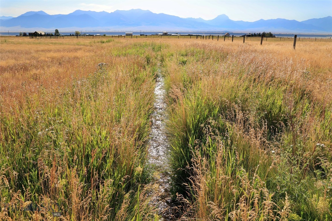 Coveted location in Shining Mountains II, situated to the east, with seasonal irrigation ditch.  Perfect horse property. These prime 6 acres check all the boxes for those seeking dramatic 360 degree views with the Madison Range, productive irrigated pastureland and easy access for your new custom home in SW Montana.  Large level lot is partially fenced making it a sweet spot for your horses with multiple build sites to take in the ever-changing landscape.  Power available in the area. Located 20 minutes from Ennis conveniences and the world-renowned Madison River, a blue-ribbon trout fishery, is just minutes away at the Varney Bridge Fishing Access.  Owners have private access to Haypress Lakes, full of trout.  Endless recreational opportunities and public lands out the back door, with Bozeman, Big Sky Resort, and Yellowstone NP each an hour drive +/-.  If you are looking for more elbow room, 18.7 total acres are available with Lots 9-11 (MLS #405843).  Photos include area views.  Create your Montana legacy today.