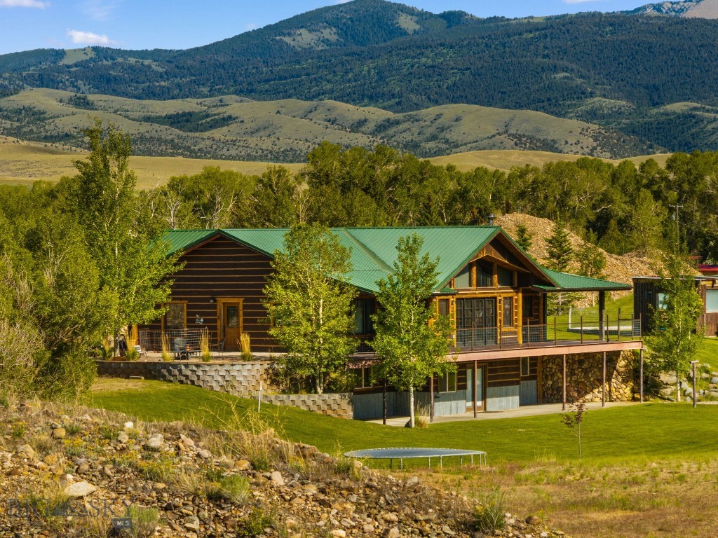 This captivating residence commands attention with its grand scale and rustic details. Expansive front windows frame breathtaking views of the Ruby mountains. Thoughtfully designed to harmonize with its surroundings, the home features nature-inspired textures and earthy tones, including corrugated tin siding paired with fir log accent. Built in 2011, this home offers open concept kitchen and living room, four bedrooms plus a bonus room easily utilized as a fifth bedroom, 3 bathrooms, spacious dining room with a bar, gym, & large laundry room. The kitchen is a chef's dream, equipped with stainless steel appliances, durable non-porous Corian countertops, and soft-close cabinets. For hobbyists or mechanics, the massive garage/shop includes a storage loft and additional living quarters. Test your green thumb in the large greenhouse. Relax next to the wood stove surrounded by cozy lodge ambiance. Unwind on the spacious front deck, take in panoramic views, and enjoy the meticulously landscaped yard with underground irrigation. This home is a true masterpiece of comfort and craftsmanship.