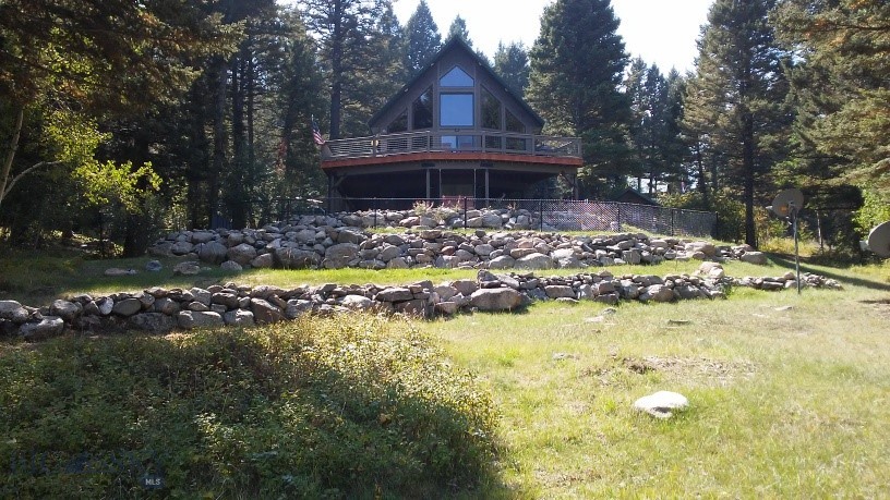Escape to your own private forest sanctuary in the heart of Montana's Tobacco Root Mountains, where abundant wildlife and the sounds of a nearby creek create a peaceful backdrop to everyday life. Located in the sought-after Mammoth Subdivision, just minutes from the South Boulder River, this exceptional turn-key mountain retreat offers comfort, craftsmanship, and adventure right outside your door.
Built in 2016, the home features durable Louisiana Pacific siding, a metal roof, spray foam insulation, a buried 500-gallon propane tank, 22 KW Generac generator, Starlink internet, security system, and approximately 1,600 square feet of Trex decking to enjoy the surrounding mountain scenery.
Inside, soaring 8' and 9' ceilings complement the dramatic 22' vaulted ceiling in the main living area, where expansive view windows bring the outdoors in. A Franklin-style propane stove creates a warm and inviting atmosphere. Solid hickory flooring spans the main level, while tile finishes the lower level and primary bath, and carpeting adds comfort to a guest bedroom and loft.
The kitchen is designed for both functionality and entertaining, featuring custom hickory cabinetry with soft-close doors and drawers, pull-out island storage, quartz countertops, KitchenAid appliances, a gas cooktop, electric oven, center island, and a spacious pantry with built-in wine cooler.
Custom craftsmanship continues throughout with solid blue pine interior doors handcrafted in Hamilton, Montana, custom blue pine trim, and Hunter Douglas window treatments. Baseboard heat with individual thermostat controls provides comfort in every room.
The home offers a primary suite with heated bathroom floors, an additional bedroom, spacious loft, and flexible lower-level living space.
Outside you'll find a heated workshop/garage with workbenches, a garden shed with pull-down work table, and a small fenced area. Surrounded by thousands of acres of public land with trails leading to alpine lakes, hunting, fishing, hiking, and endless recreation. Conveniently located approximately 65 miles from Bozeman and 50 miles from Butte.
Offered fully furnished and completely turn-key—just bring your toothbrush and start enjoying Montana mountain living.