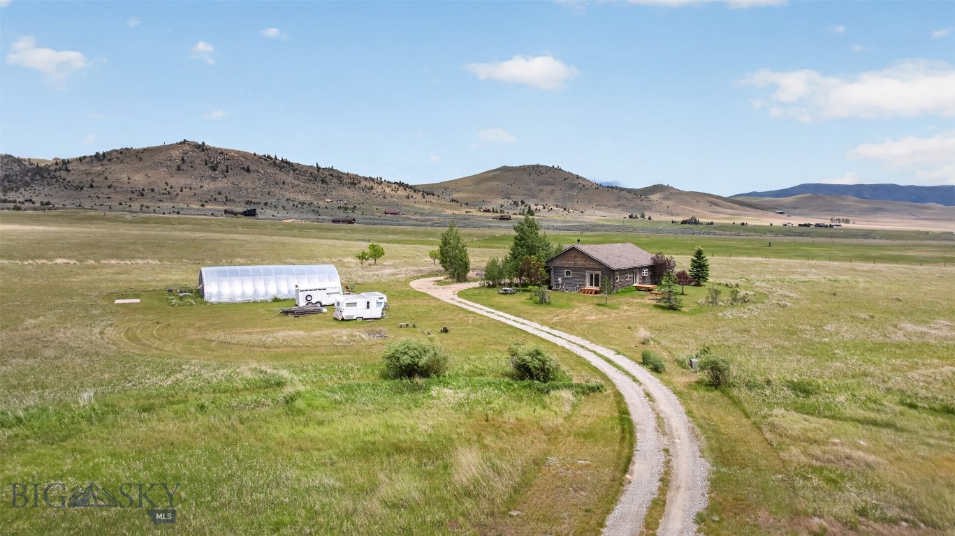 Welcome to your Montana retreat on 10.5 scenic acres in the heart of the Madison Valley. Nestled among expansive ranchlands with breathtaking 360-degree mountain views, this charming log home offers the perfect balance of privacy, comfort, and outdoor adventure.

Th cozy 3-bedroom, 2-bathroom home features warm log construction, a wood-burning stove that creates the perfect gathering place on cool Montana evenings, and an attached two-car garage for convenience and storage. Large windows frame spectacular views in every direction, bringing the beauty of the surrounding landscape indoors.

The property is well suited for hobby farming, gardening, or simply enjoying the Montana lifestyle. A productive greenhouse has been used for flower production, while valuable water rights provide additional versatility for irrigation and future agricultural pursuits.

Located just minutes from the Revenue Flats Recreation Area, you