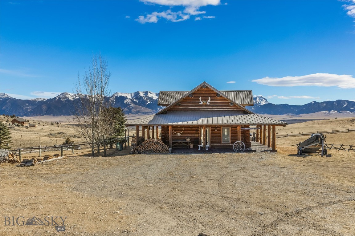 Set just outside of Ennis yet still within the Ennis community, this beautiful 2216± square foot (per owner) custom log home offers privacy, views, and Montana character on 5.197± acres of partially fenced open ground. With three levels of living space, the home is designed to capture both comfort and functionality while taking full advantage of its scenic setting. The main level features the kitchen, dining, and living areas anchored by warm log construction, pine hardwood floors, and a wood stove that adds both charm and comfort. The kitchen offers the opportunity for refreshed finishes while maintaining the home's inviting layout. The lower level includes the primary bedroom, bathroom, mechanical room, and laundry. A sliding glass door opens to a deck facing east toward the Madison Range, a perfect spot to take in morning light and mountain views. The upper loft provides flexible space for guest accommodation, an office, or hobbies. Outdoor living is a highlight with a wraparound covered porch that invites you to relax and enjoy the surrounding landscape and wildlife. The property includes two 30x60 new pole barns, offering a blank slate for storage, shop space, livestock, or recreational equipment. A small dry cabin and additional shed add further versatility for guest overflow, a studio, or extra storage. Located close to the Madison River and abundant public lands, this property provides convenient access to fishing, hiking, hunting, and endless outdoor recreation. This subdivision boasts private stocked lakes. The home is served by a well and septic, with fiber internet available to the house but not yet connected. Kitchen does not have all the cabinets & can be finished your way.