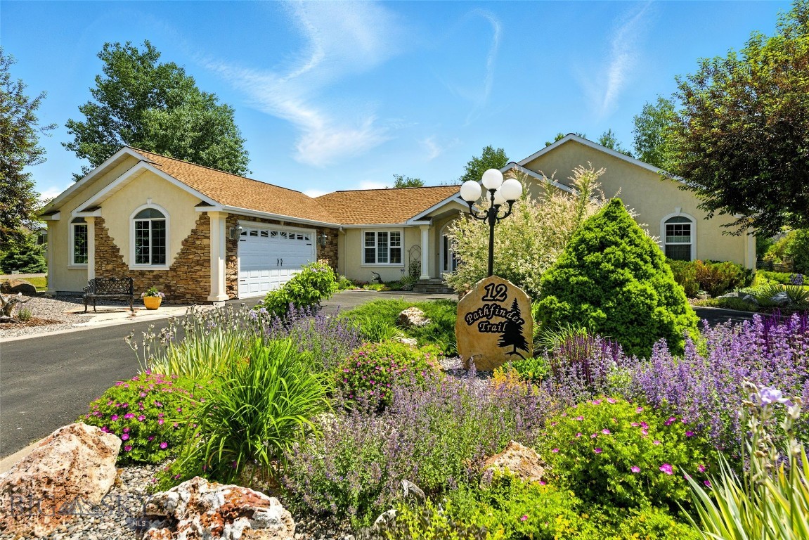 Better than new, this 2,695± sq ft custom home in Valley Grove reflects thoughtful design, quality craftsmanship, and exceptional care throughout. Set on a beautifully maintained 0.65± acre corner lot, the property is framed by mature landscaping and a private backyard retreat featuring stone-edged garden beds, expansive stone patios and walkways, and a 20-zone underground sprinkler system. Inside, the single-level floor plan is both elegant and functional, highlighted by vaulted ceilings, rich hardwood floors, and refined architectural details. Marble window and door casings, custom woodwork, and carefully selected finishes elevate every space. The kitchen anchors the home with solid-surface granite countertops, an antique-style island, and custom cabinetry, flowing naturally into a comfortable dining area ideal for everyday living. A nearby formal dining or sitting room, accented by classic columns and travertine details, offers a more refined setting for entertaining or quiet conversation. The living room serves as a welcoming centerpiece, featuring a gas fireplace with a tiled mantle, live-edge wood accents, and abundant natural light. The home includes two primary suites, each with a private, well-appointed bath. All three bedrooms feature French doors that enhance the home’s timeless aesthetic while filling each room with light. The third bedroom—currently used as an office—includes reinforced built-in shelving designed for display of substantial artwork or collections. Each bathroom is thoughtfully designed with antique-style vanities and period-inspired mirrors, adding character and warmth to daily routines. The home has been lightly lived in, meticulously maintained, and consistently updated, offering true move-in-ready condition. Additional features include an attached, oversized two-car garage with a built-in hobby or storage room, along with a backyard shed providing flexibility for gardening or storage needs. Located in Valley Grove, one of Bozeman’s most established communities, residents enjoy access to a neighborhood park, pond, and volleyball court—just minutes from downtown Bozeman, Montana, Montana State University, and major commuter routes. A rare opportunity to own a home where timeless design meets everyday ease in an exceptional setting.