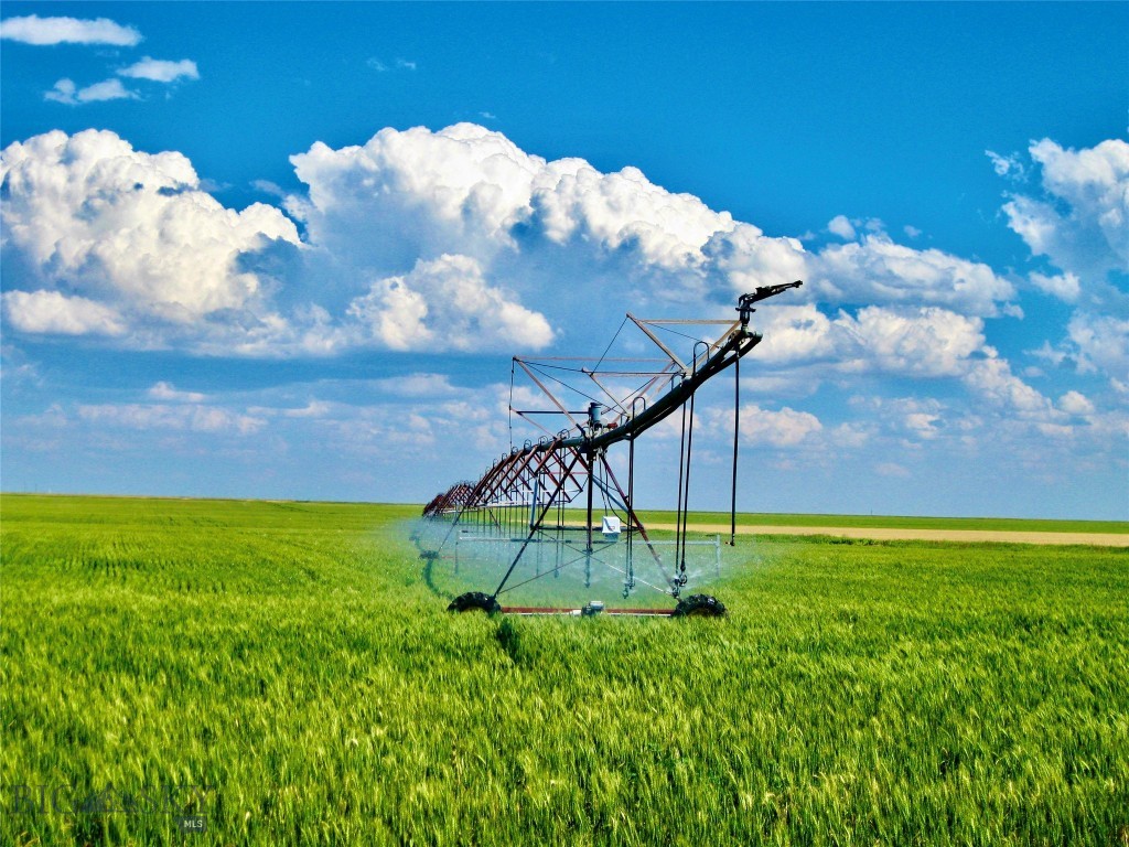 Located just 6.5 miles from Valier, Montana, this 1,236± deeded acre farm and ranch offers a rare combination of productive irrigated farmland, livestock infrastructure, significant water rights, and year-round recreational appeal. With 920 shares of Pondera County Canal & Reservoir Company water, eight center pivots irrigating approximately 768.59 acres, and additional flood-irrigated and dryland acreage, the property is well-positioned for continued agricultural productivity. Improvements include over 140,000 bushels of grain storage capacity with multiple aerated bins, a large Quonset building, feedlot facilities with four pens and 400 feet of concrete bunks, automatic waterers, corrals, a heated 48’ x 30’ shop, and supporting infrastructure. A 150 acre-foot reservoir permitted for trout stocking enhances both operational water management and recreational value. Historically planted to wheat, barley, pulse crops, alfalfa, and forage, the property benefits from strong soils and established production history. Located near Lake Frances and within reach of the Rocky Mountain Front, Bob Marshall Wilderness, and Glacier National Park, the ranch offers exceptional hunting, fishing, and outdoor access in addition to agricultural strength.